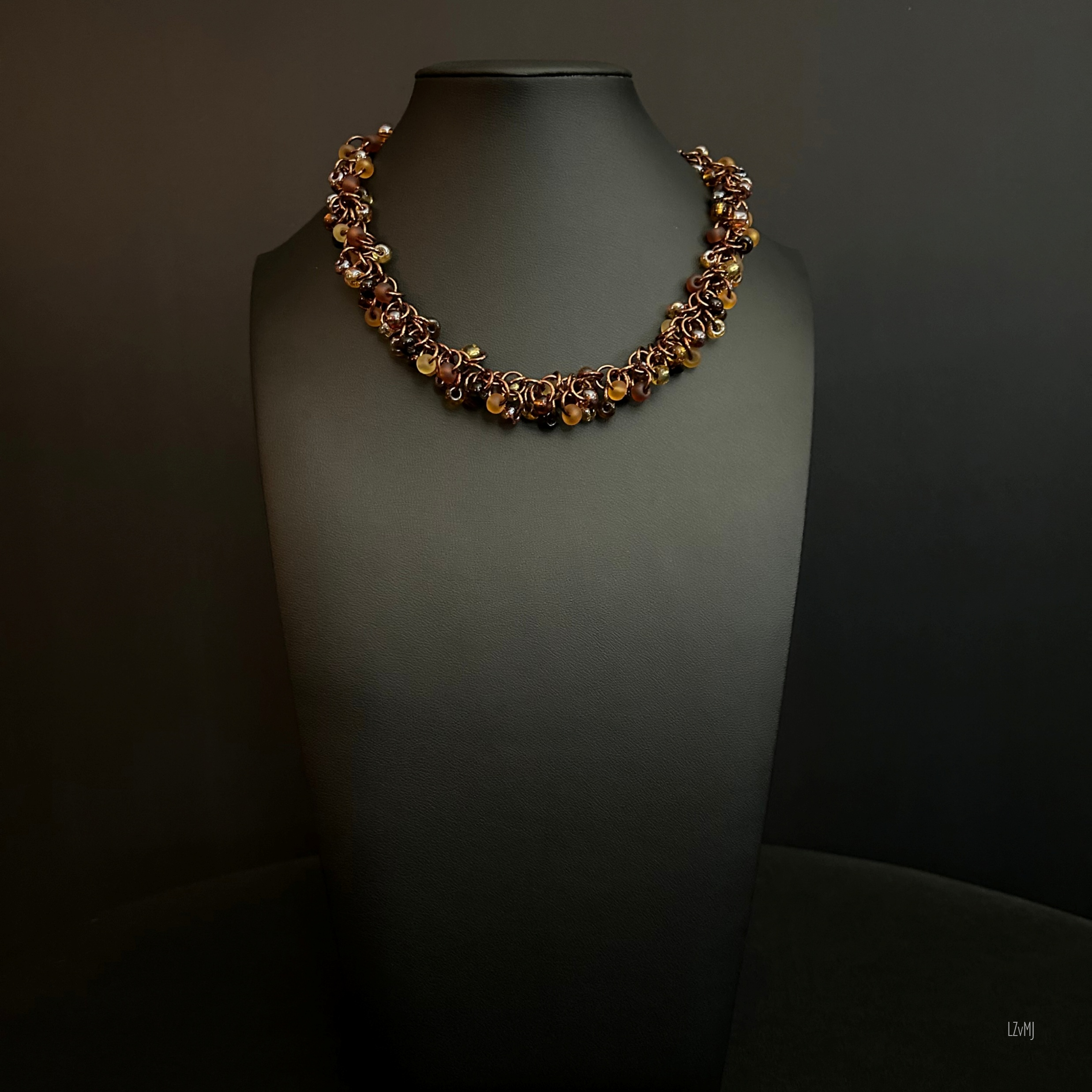“Full view of the bronze shaggy‑loop necklace with amber, brown, and black beads.”