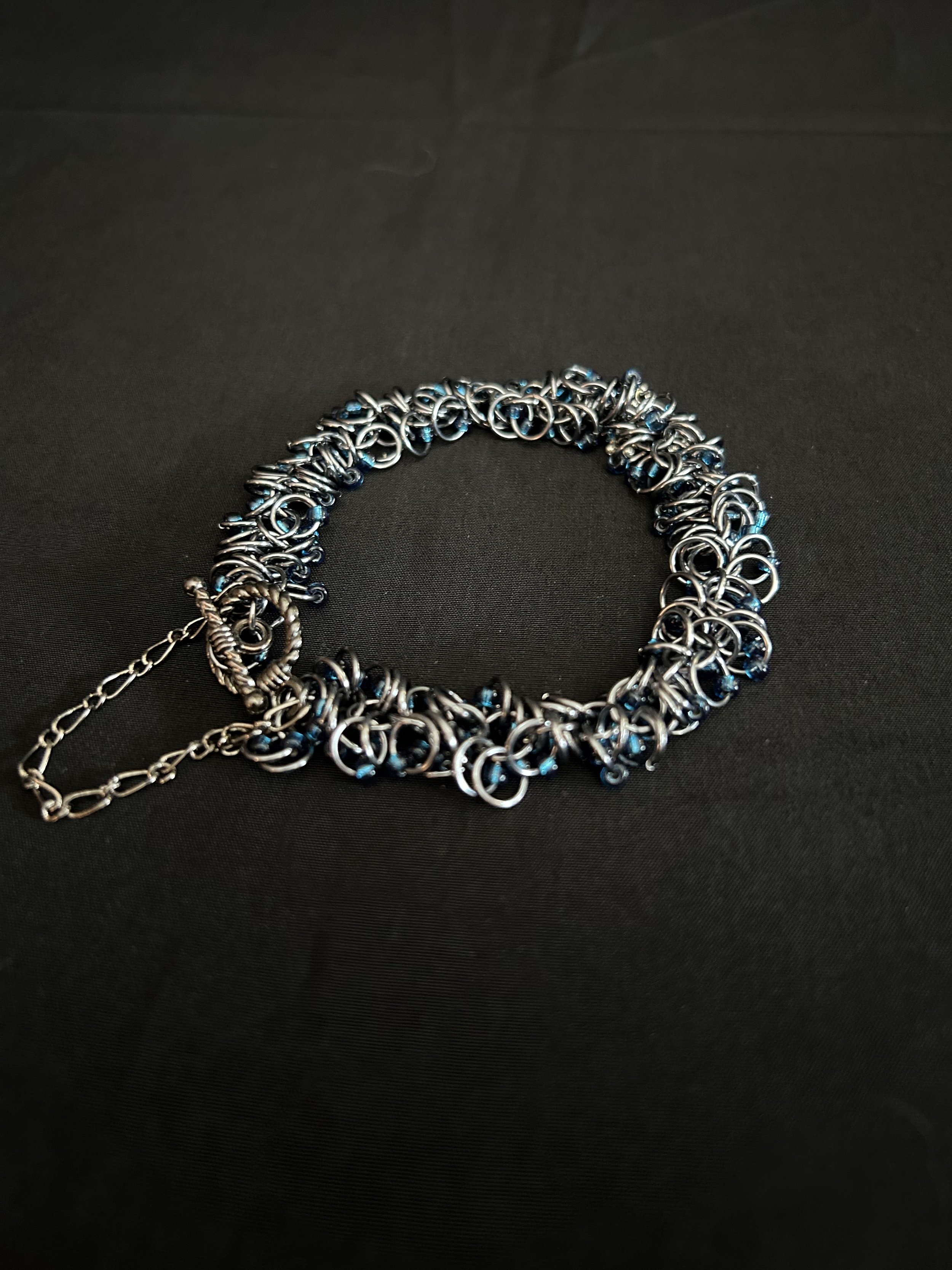Midnight River bracelet shown laid flat on a light background, highlighting the Black Ice rings and midnight blue beads