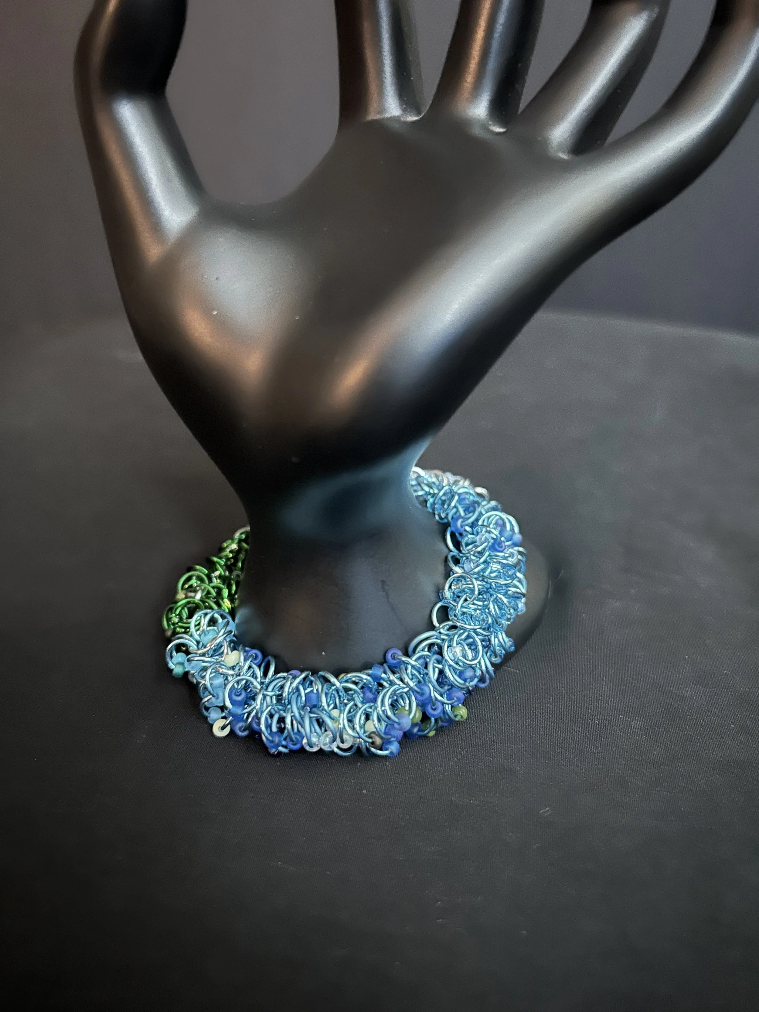 “Blue Ridge Mountain Bracelet shown at an angle, highlighting the forest‑to‑mist gradient and handwoven chainmaille texture.”