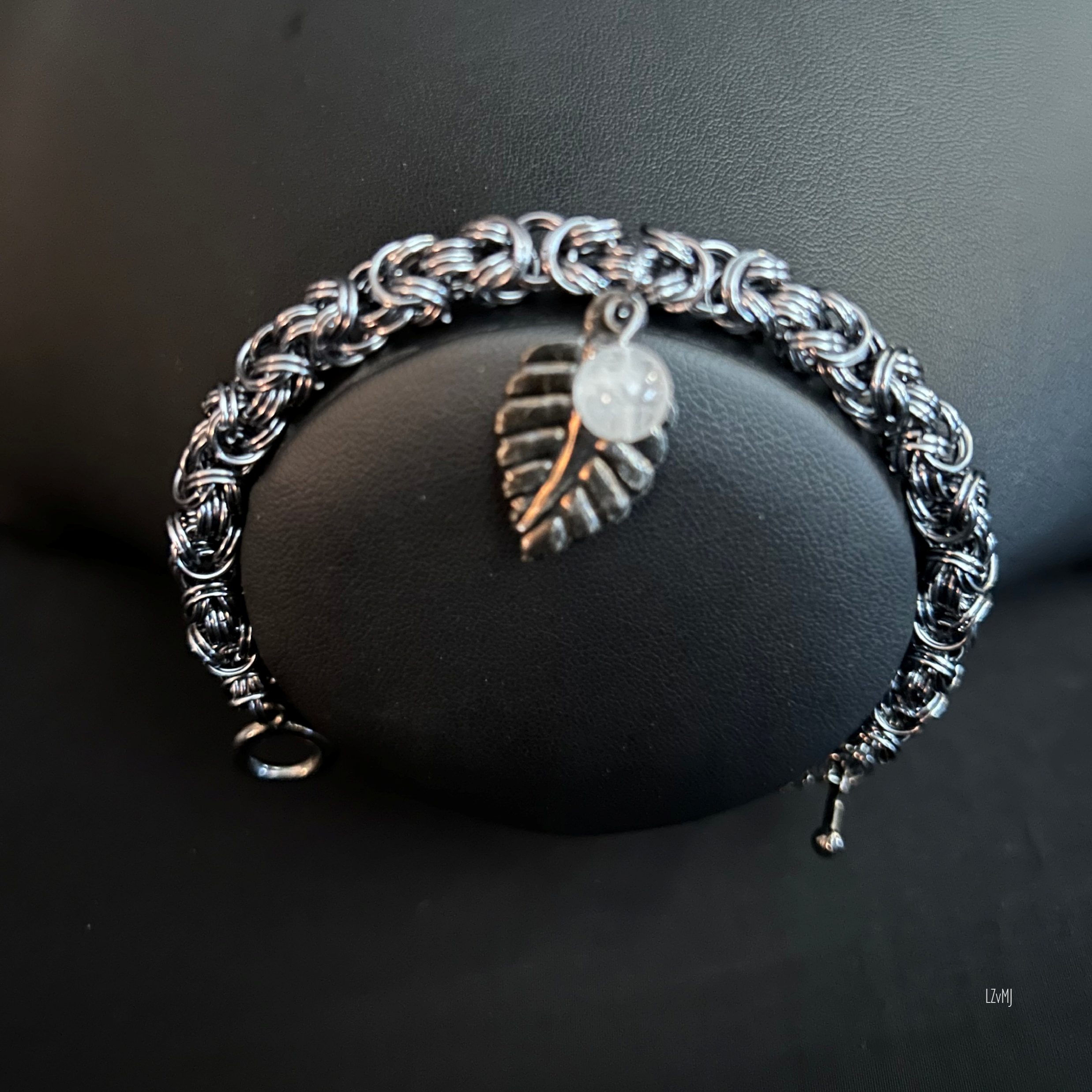 “Black Ice Byzantine bracelet with leaf charm and moonstone displayed on a black bust.”
