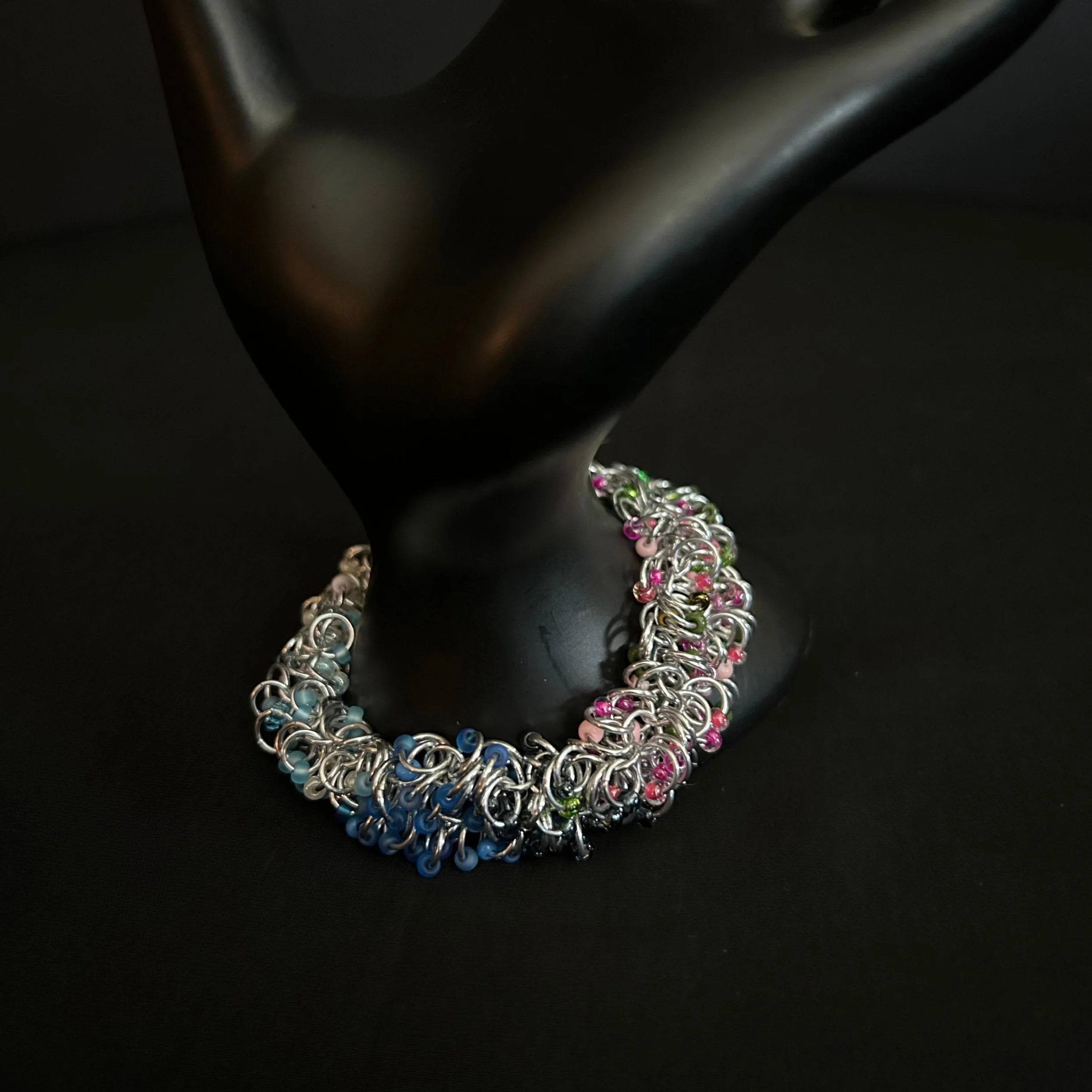 “Spring‑tone chainmaille bracelet displayed on a hand prop.”