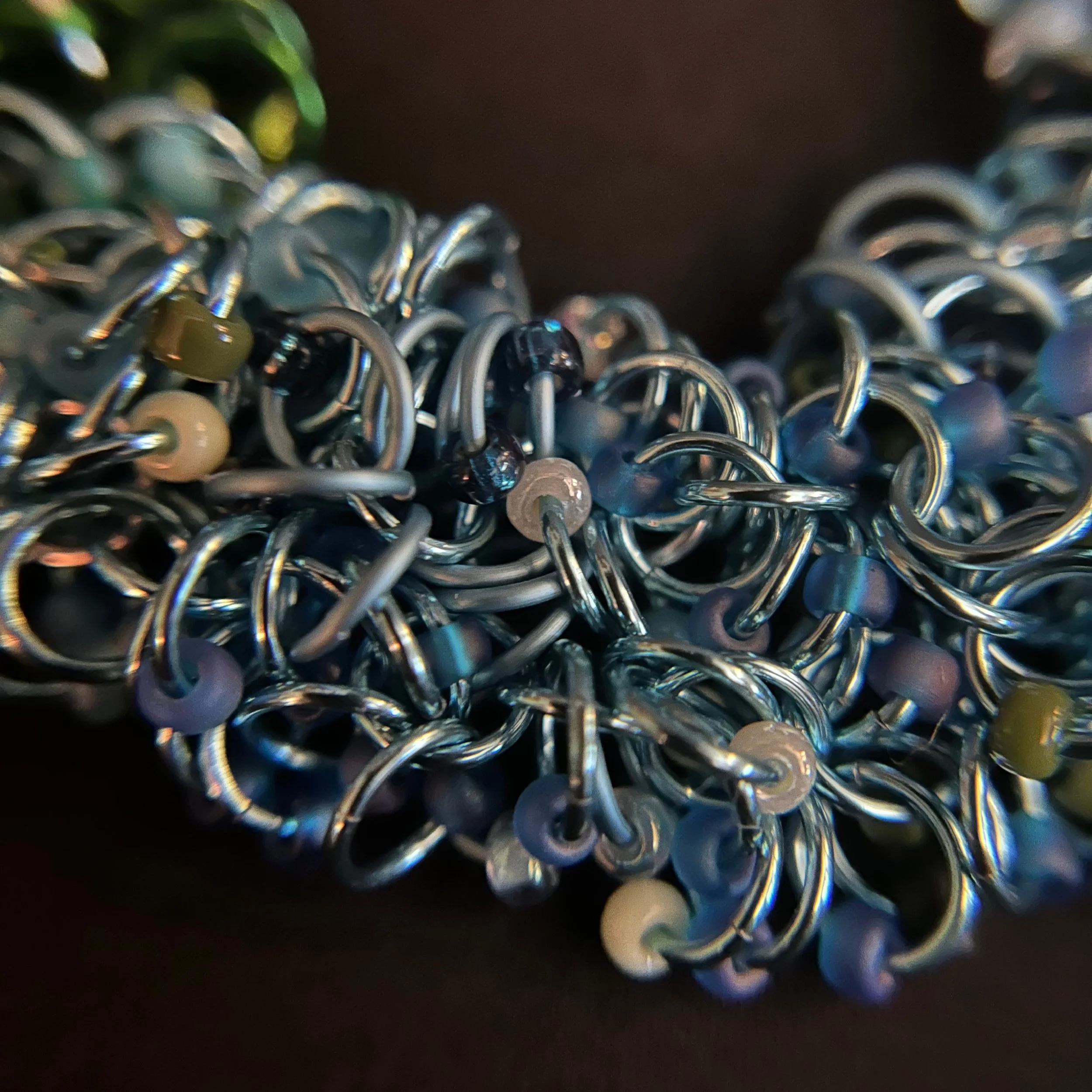 “Detail of the aluminum rings with green, teal, and blue Miyuki beads.”