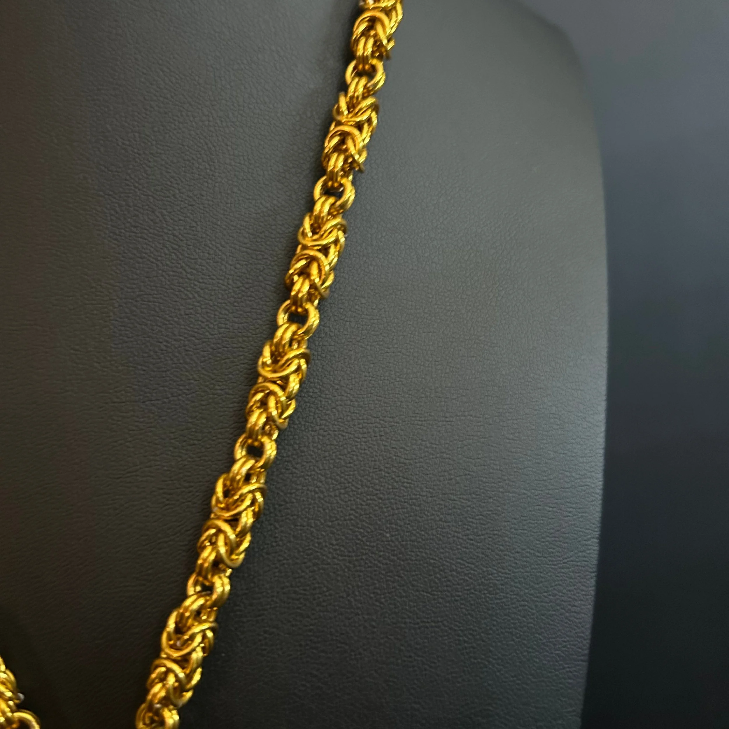 “Detail of the gold‑tone aluminum chainmaille weave.”