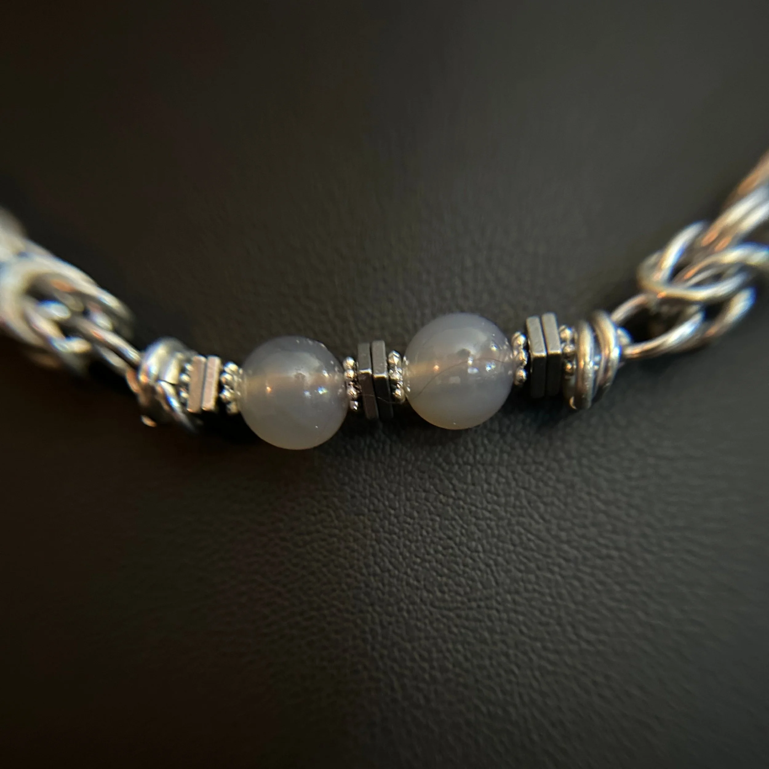 Detail of the Moonlit Harbor necklace with two gray beads framed by small hematite spacers and chainmaille links