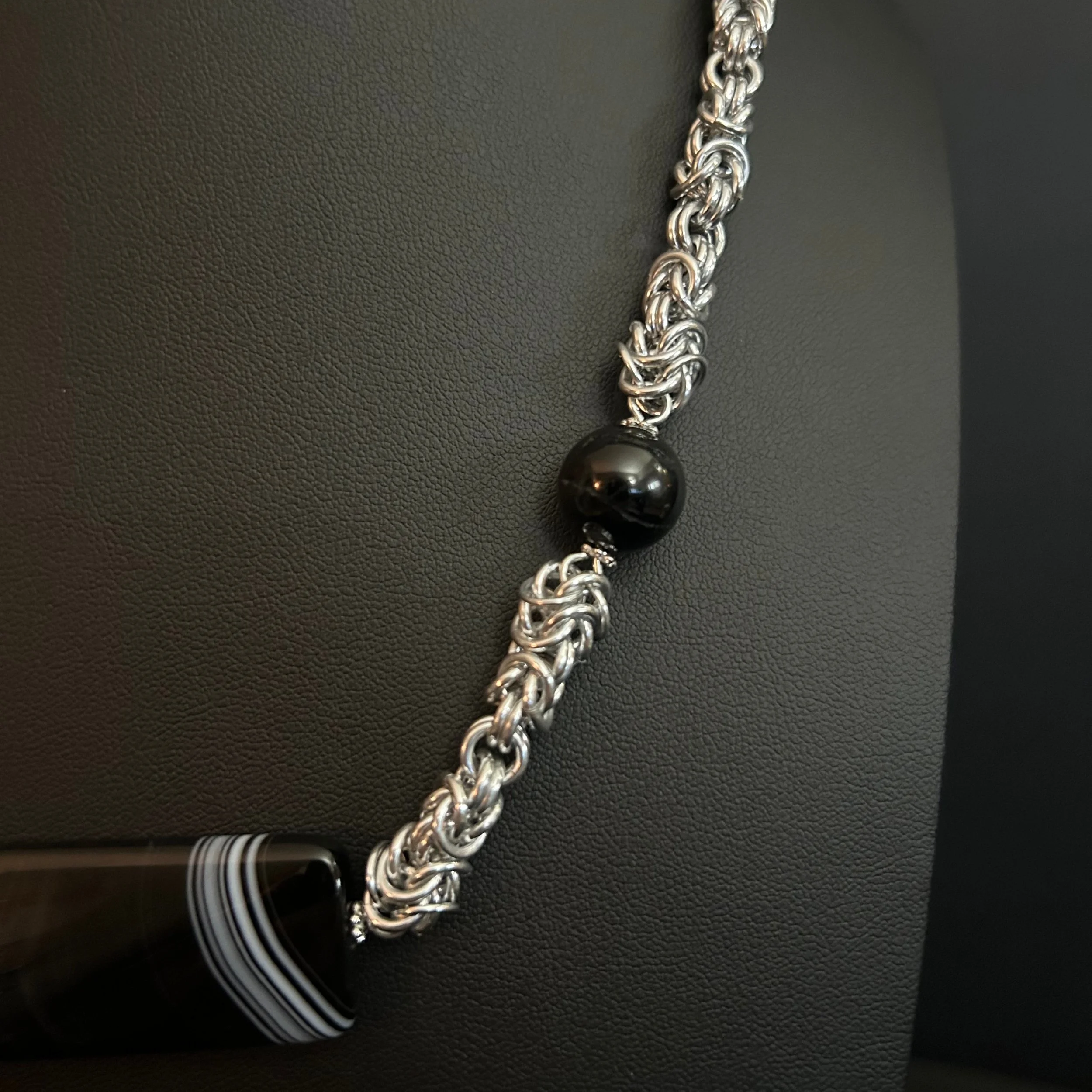 “Detail of the aluminum chainmaille rings with black tourmaline bead accents.”