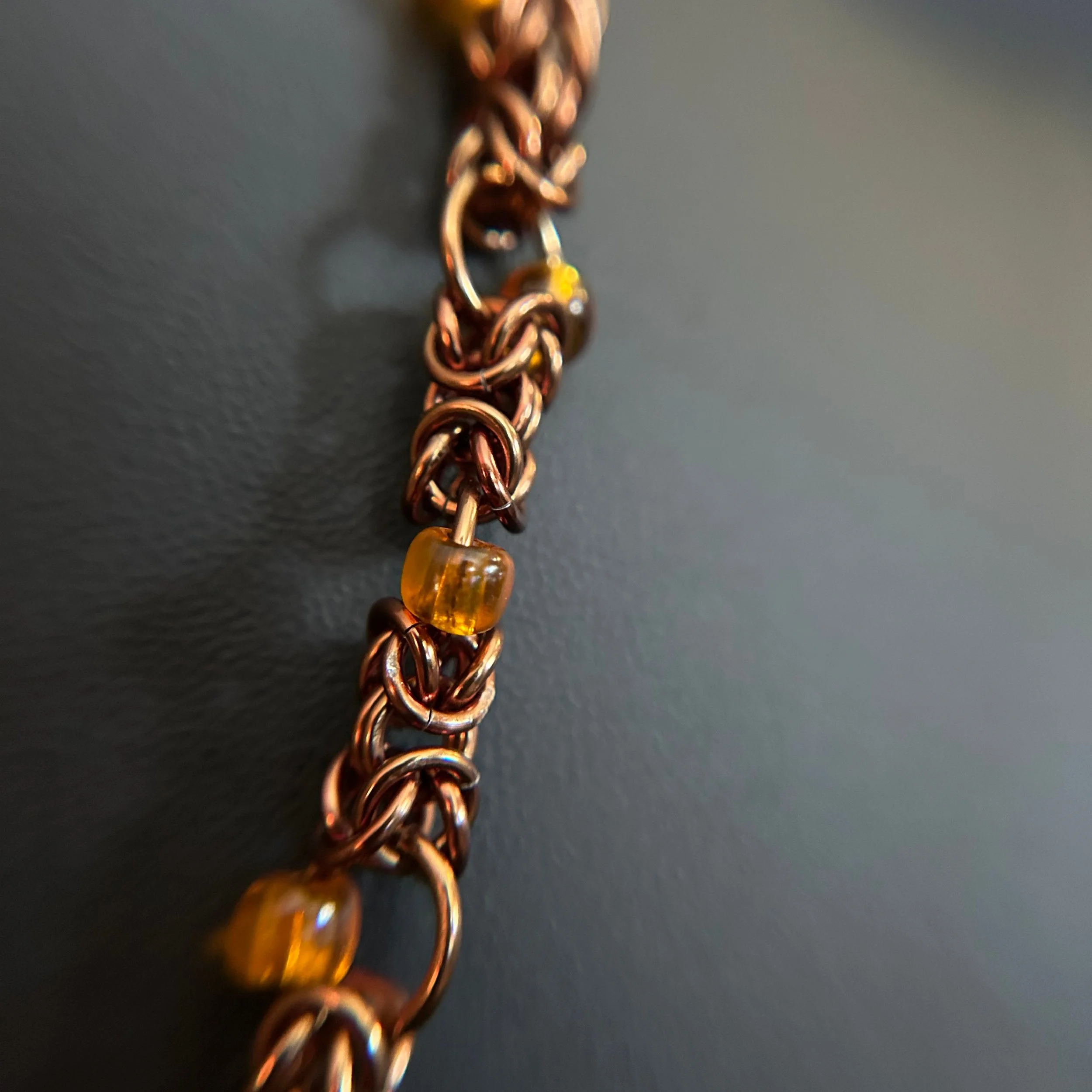 “Close-up of the bronze aluminum chainmaille rings and amber bead accents.”