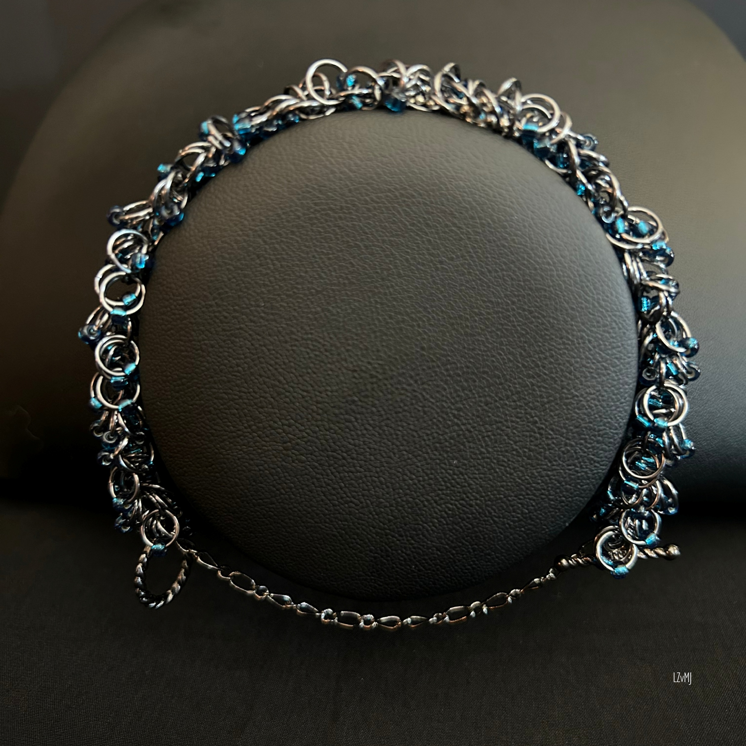 “Black Ice bracelet with dark blue beads displayed on a black jewelry bust.”