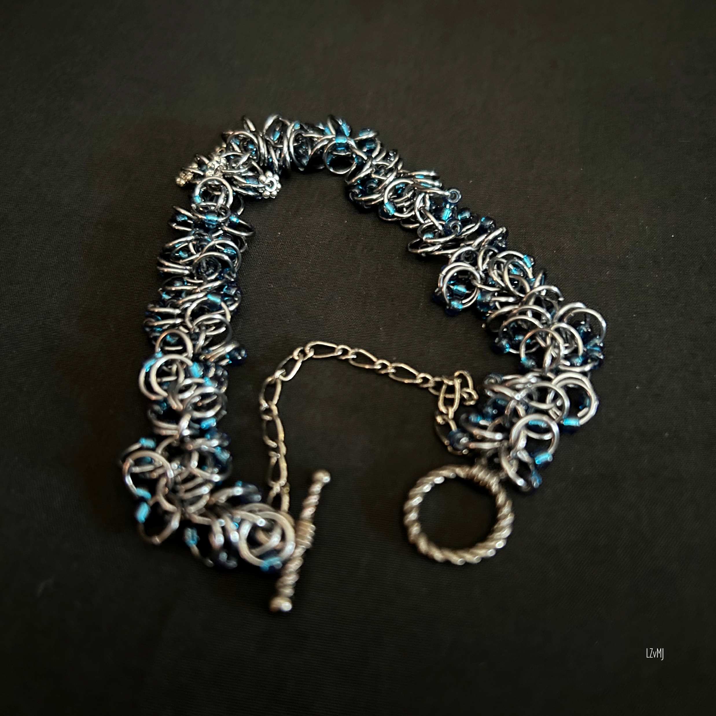 “Black Ice bracelet with dark blue beads displayed on a black jewelry bust.”