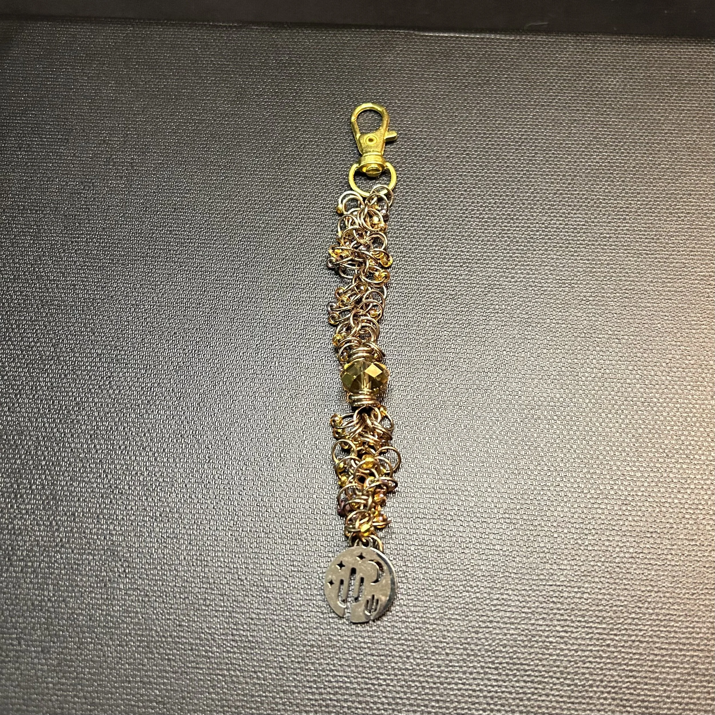 “Gold‑tone cactus, moon, and stars cut‑out focal on champagne ring purse charm.”