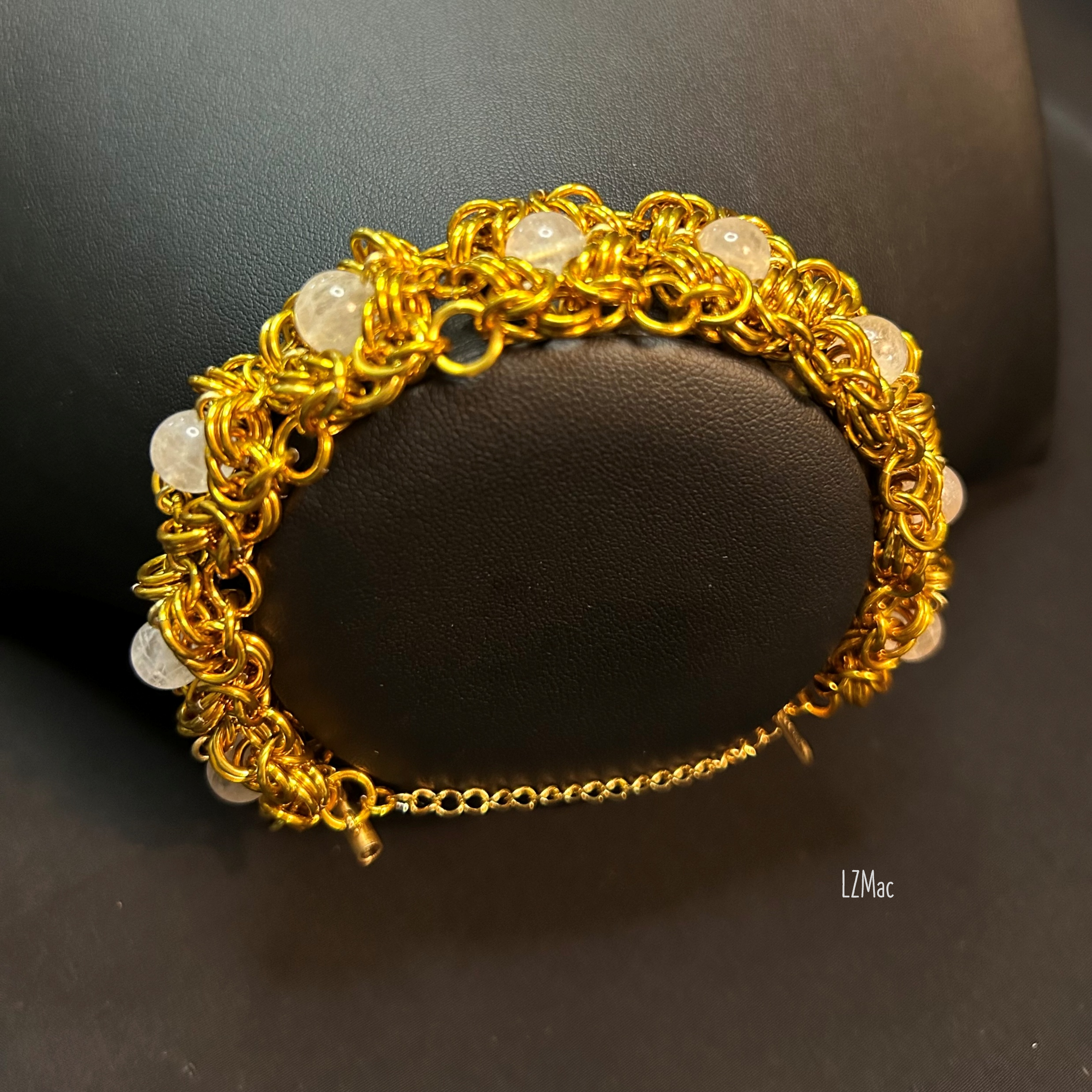 Moonlit Rosette Bracelet displayed on a jewelry bust, showing the wide gold rosette weave and luminous moonstones.