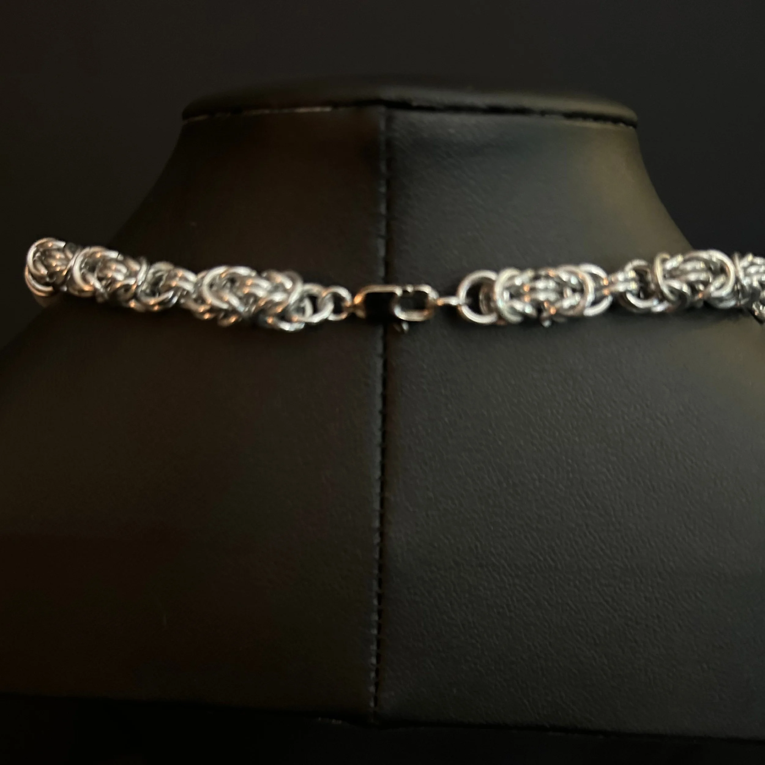 Moonlit Harbor necklace clasp and chain detail, showing interlocking silver rings against a black background