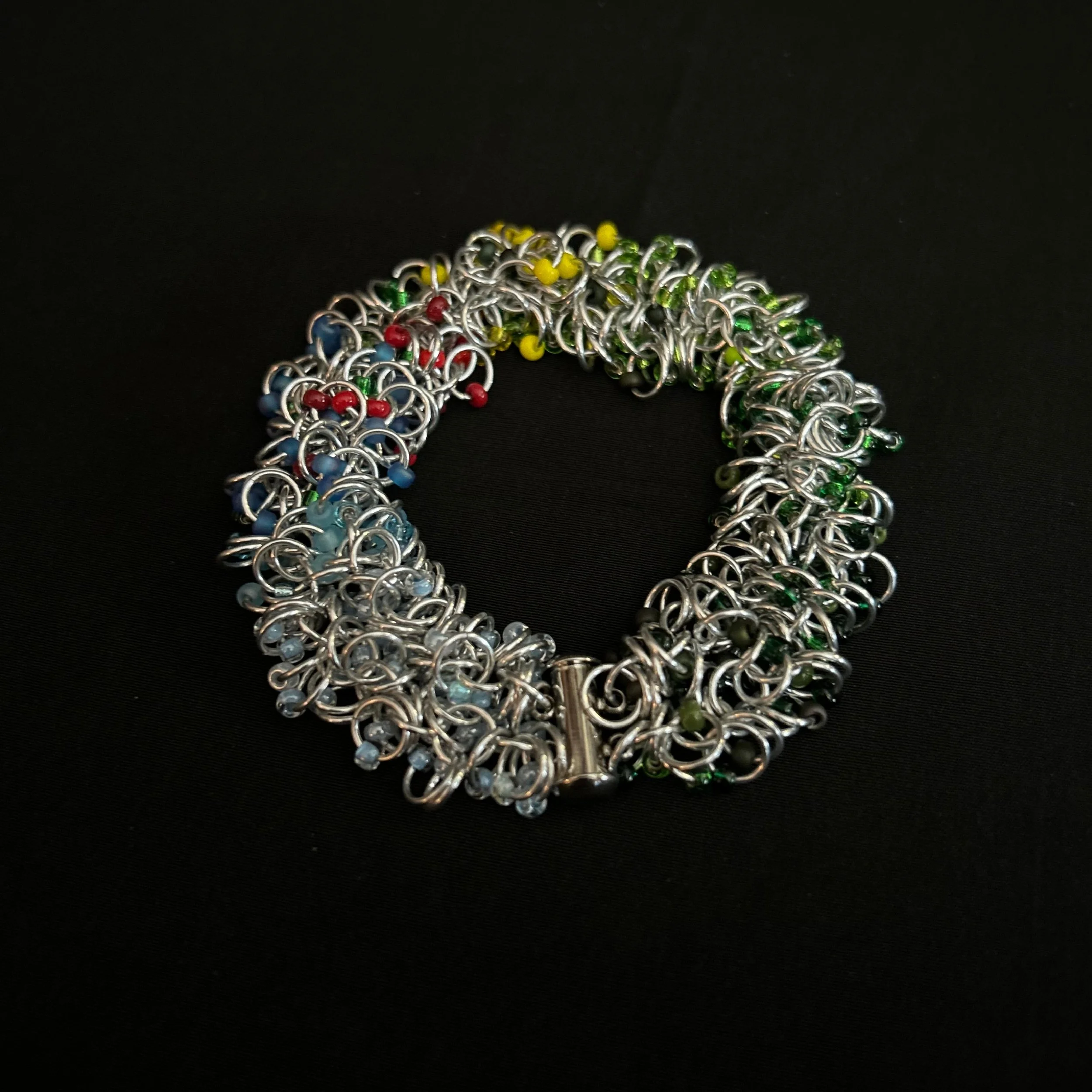 “Blue Ridge Summer bracelet laid flat in a round shape showing aluminum rings and colorful beads.”