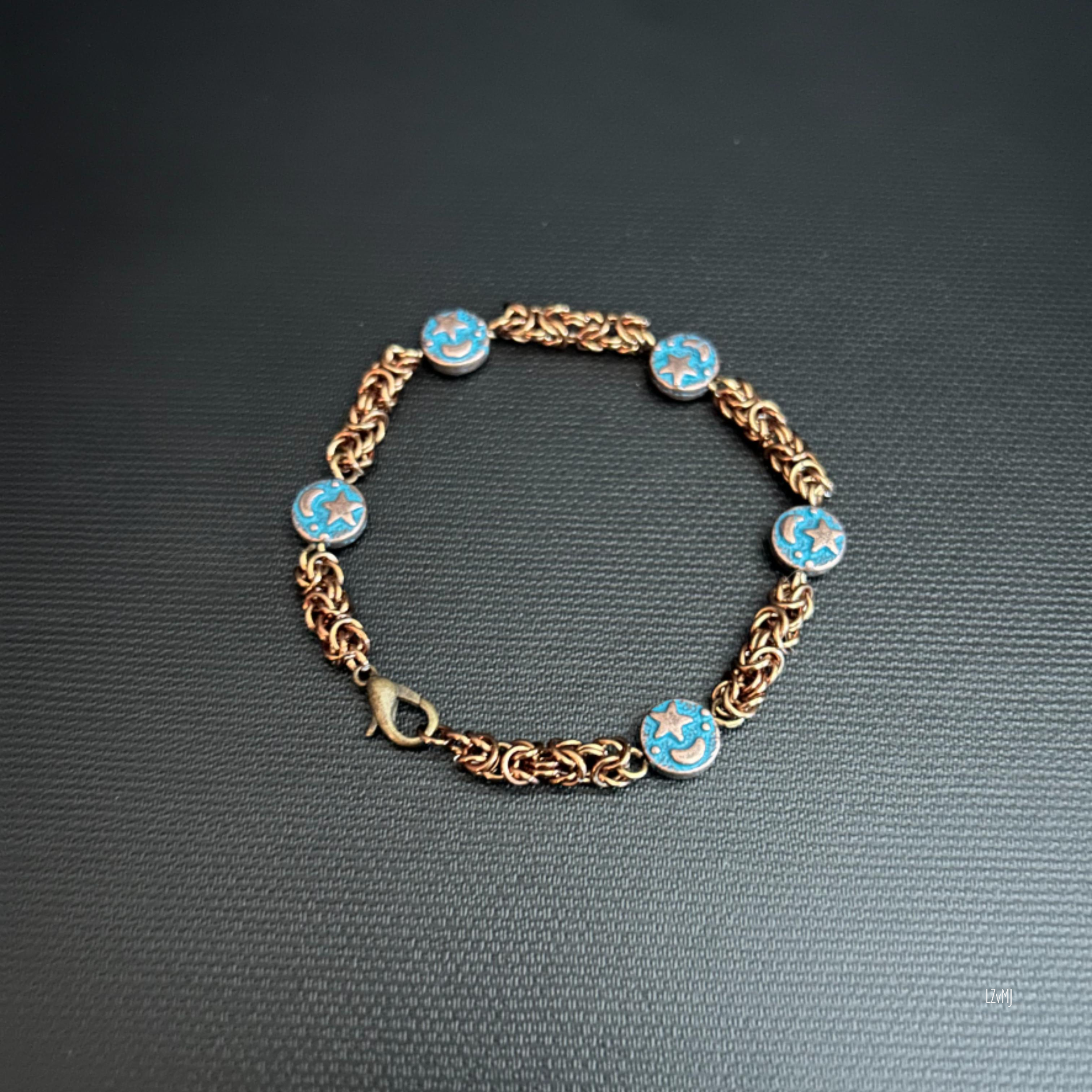 Starhaven Orbit bracelet with bronze rings and blue celestial charms on a dark background