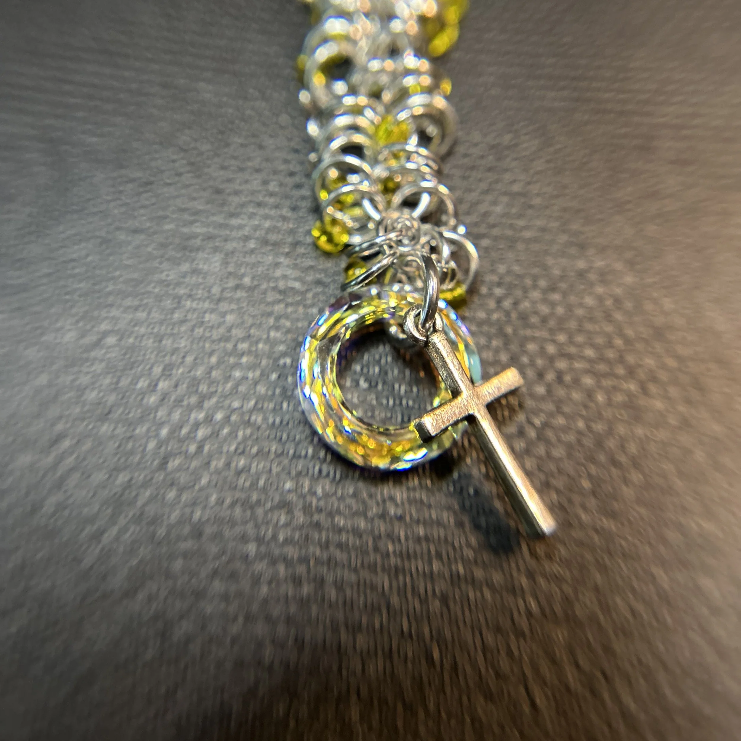 Close-up of Swarovski crystal donut and silver cross charm on silver and yellow accent purse charm