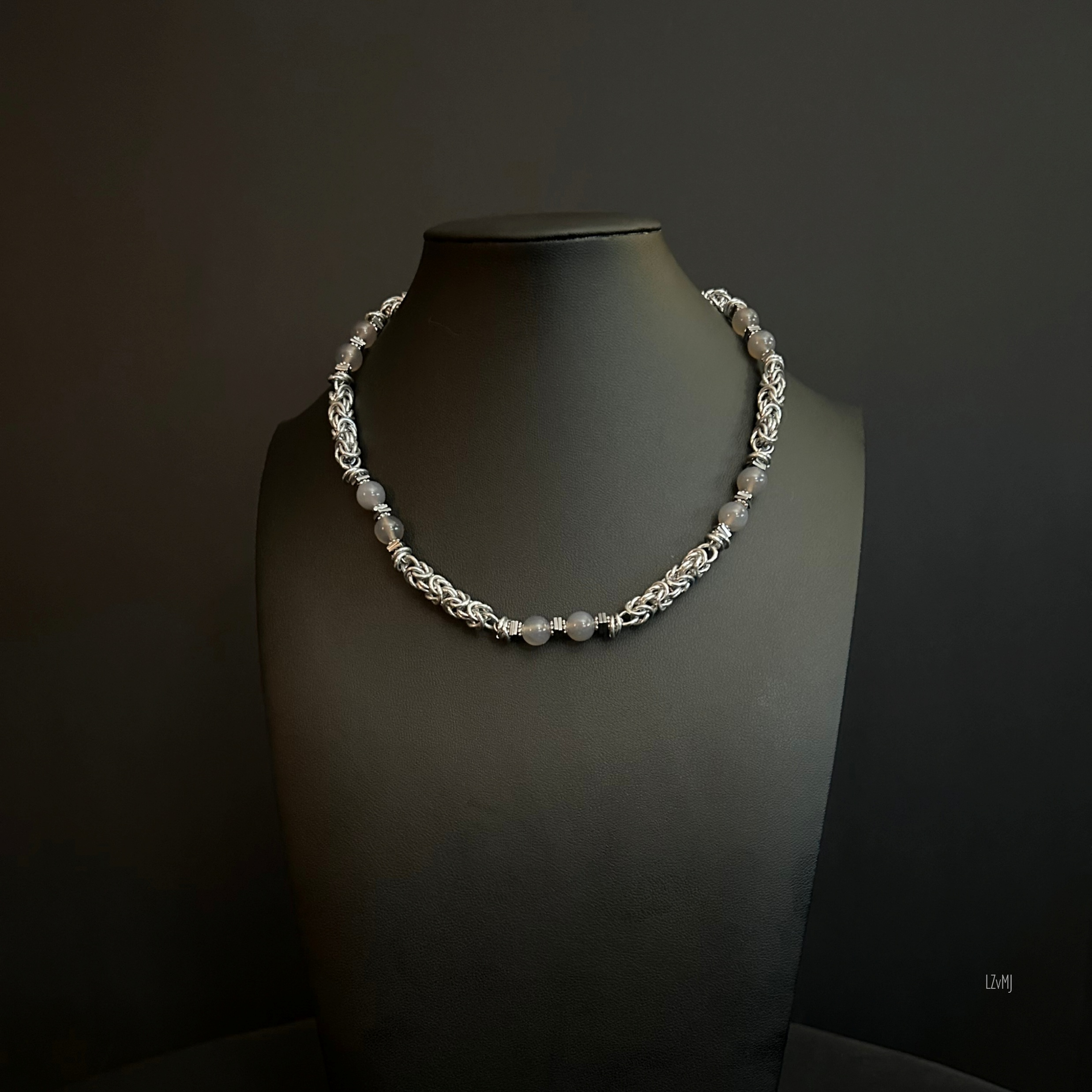 Moonlit Harbor necklace shown on a black bust, featuring interwoven silver links and evenly spaced gray beads