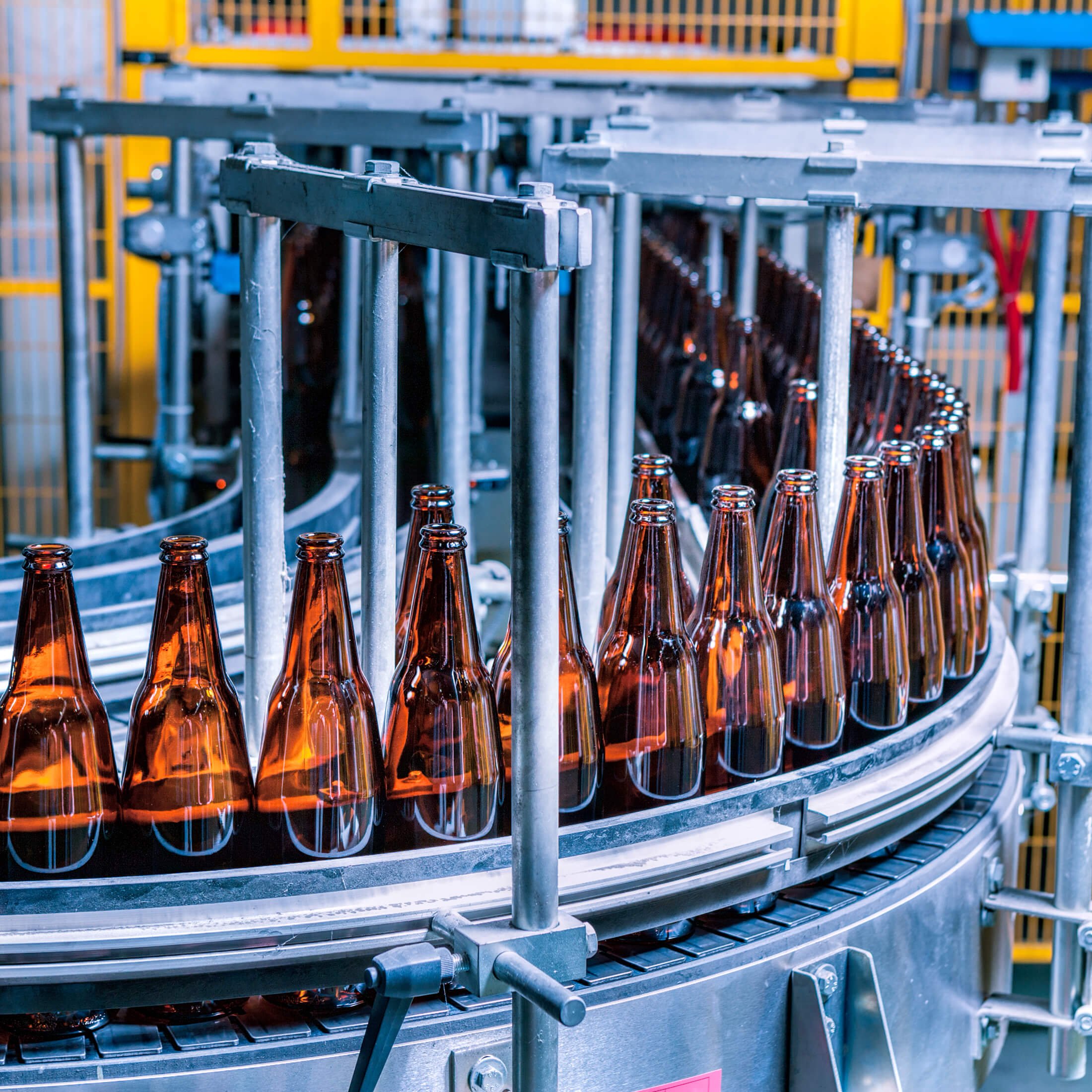Factory conveyor belt with bottles of beverage being filled and capped.