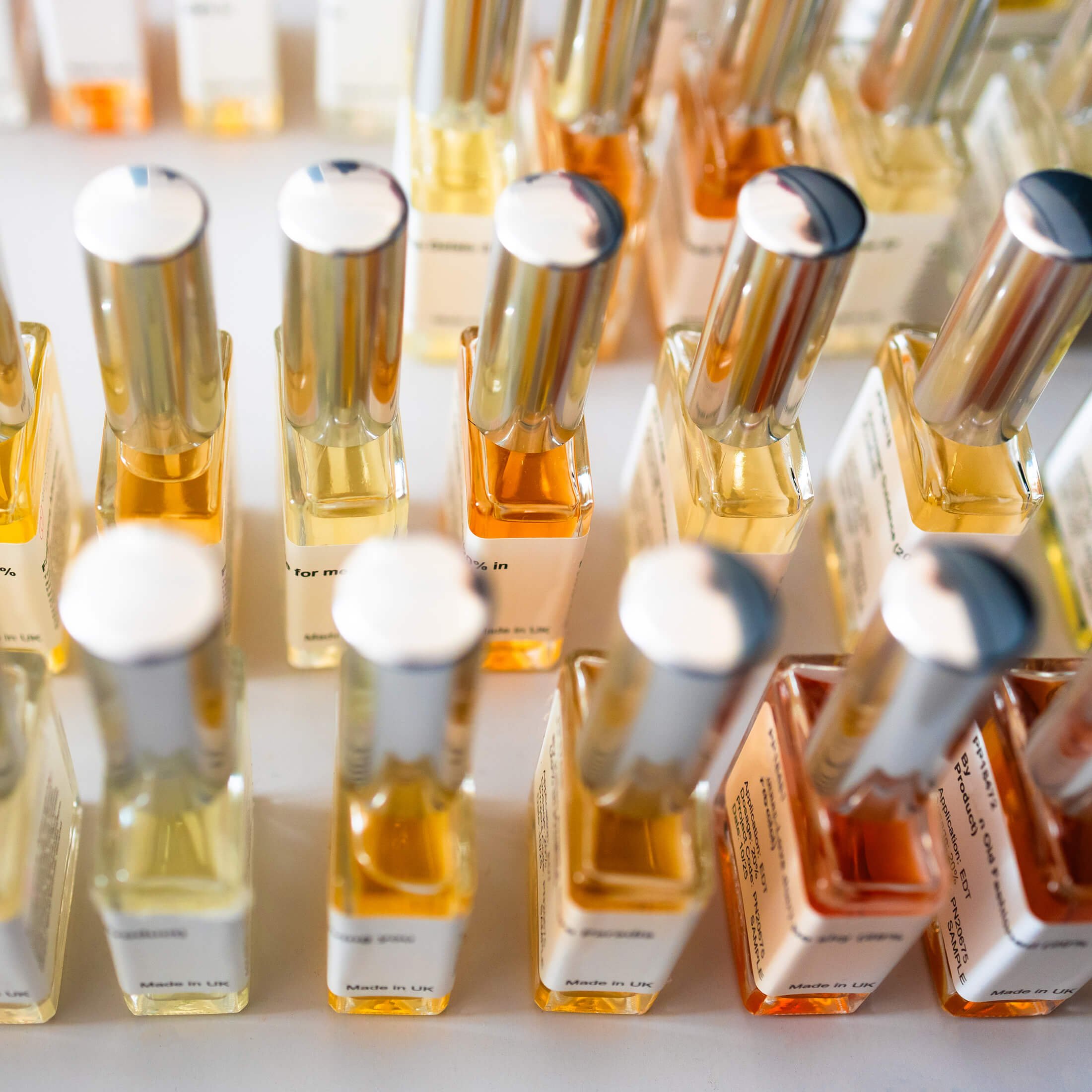 Close-up of rows of bottles with white and orange labels, blurred at the top and focused on the bottom, with visible text indicating they are made in the UK.