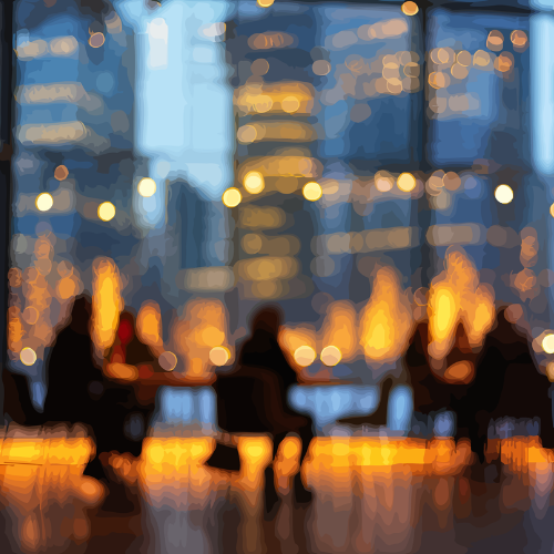 Blurred cityscape at night with illuminated skyscrapers and people sitting around tables outdoors.