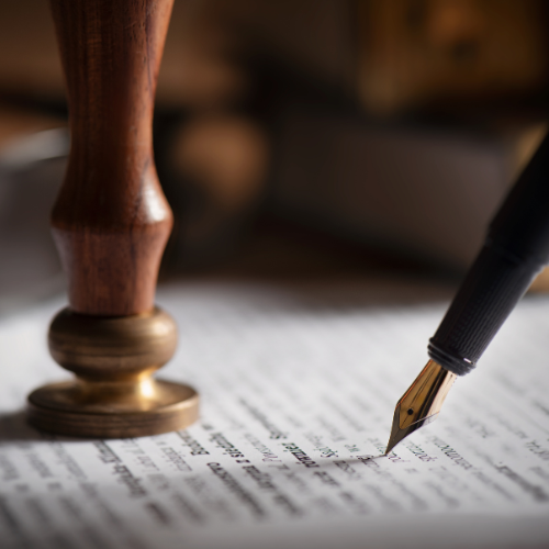 Close-up of a fountain pen writing on a document with a wood stamp nearby.