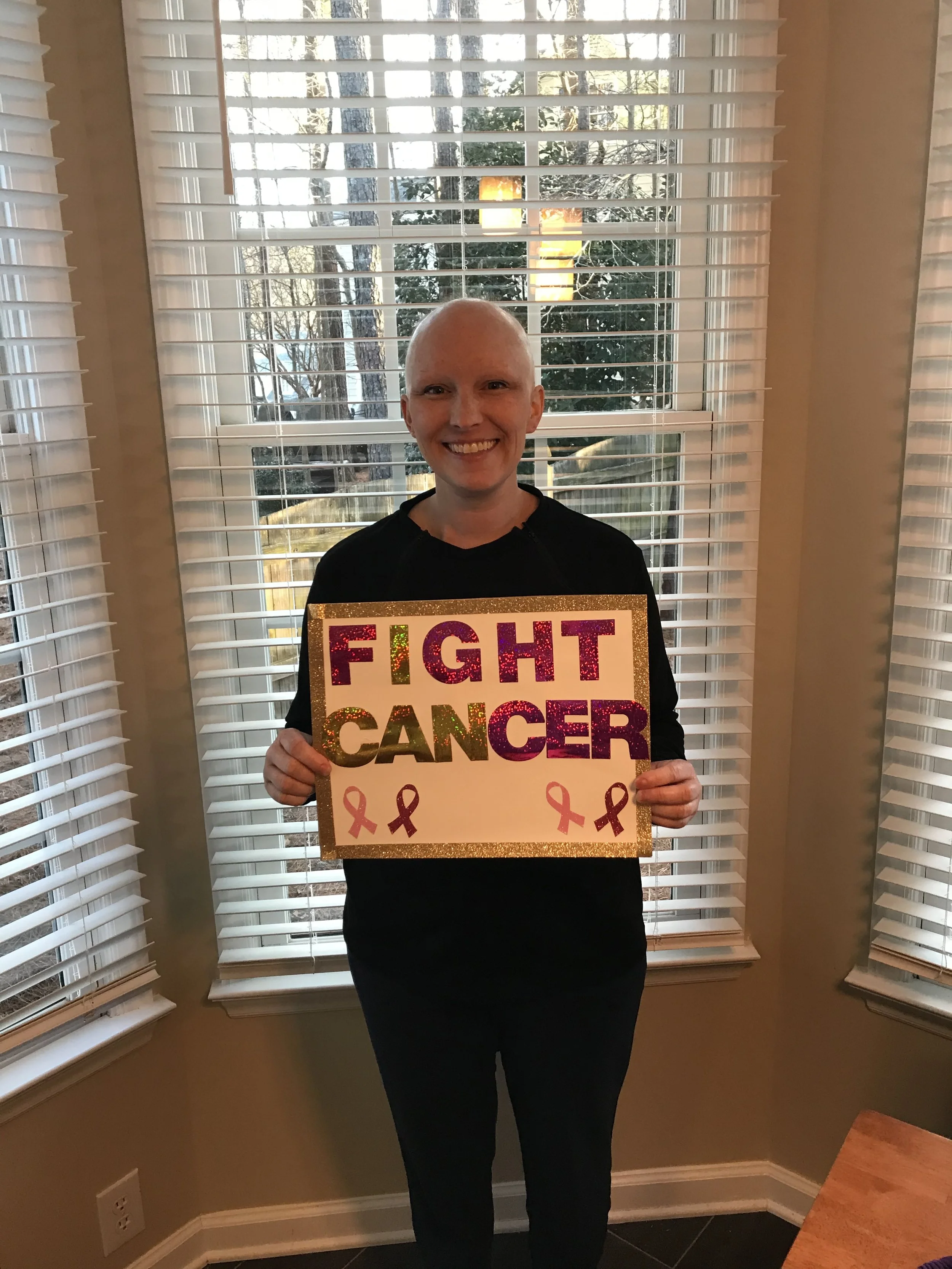 Amanda on her last day of chemo, holding a Fight Cancer sign