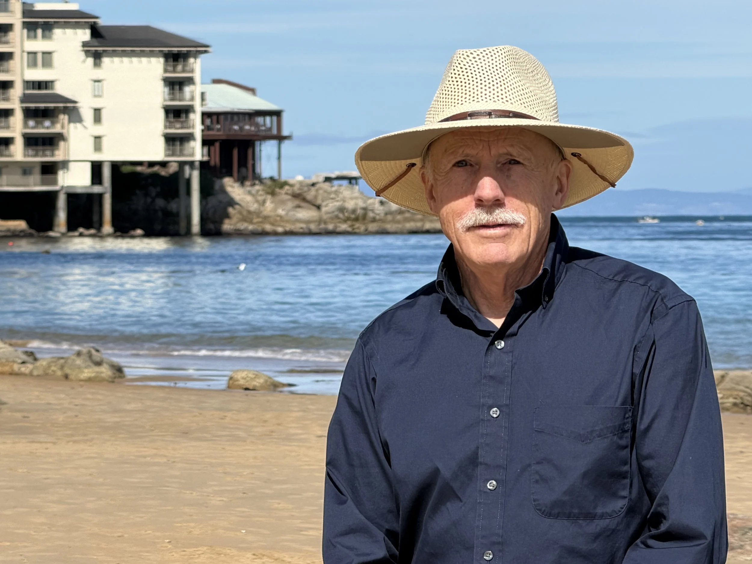 Monterey D1 Candidate Tom Reeves stands in front of the ocean at San Carlos Beach