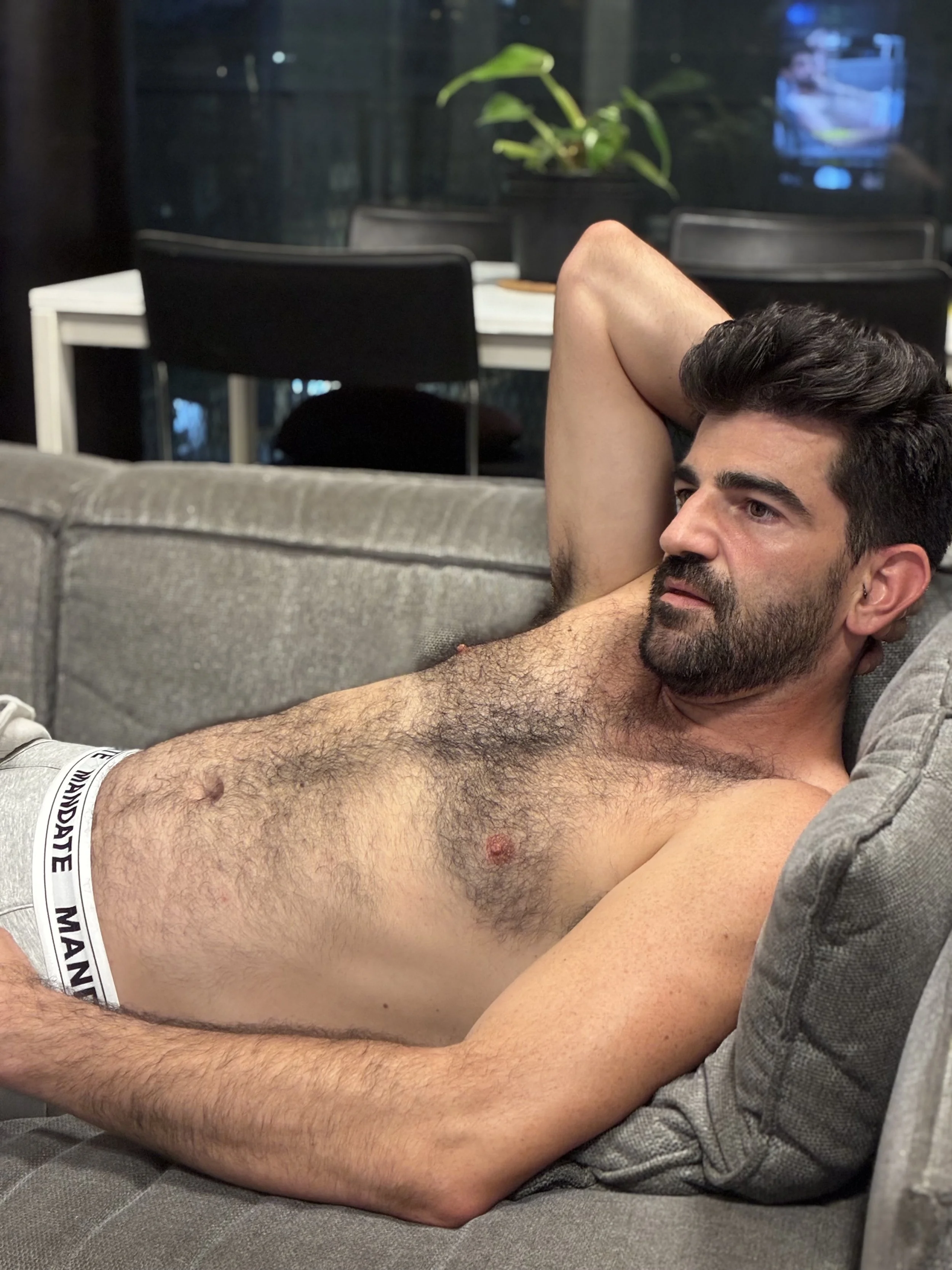 Man sitting in jock underwear on sofa 