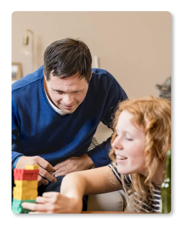 Un homme et une jeune fille jouent à un jeu de société avec des blocs colorés dans une pièce confortable.