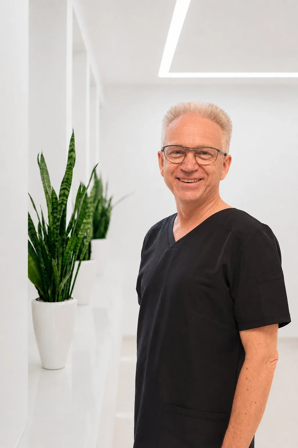 Zahnarzt Burkhard Hagemenn steht im Zahnmedizinischen Zentrum Zoubie neben einer Pflanze in weißem Topf.