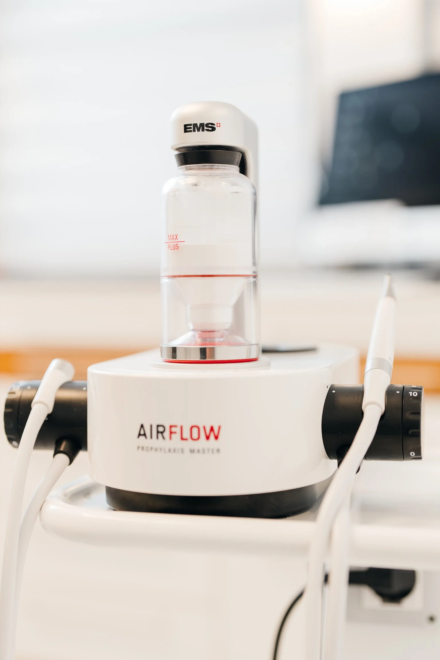 Ein Medizingerät namens AIRFLOW mit einem transparenten Behälter, der Wasser enthält, und angeschlossenen Schläuchen und Kabeln, das in einem medizinischen Umfeld steht.