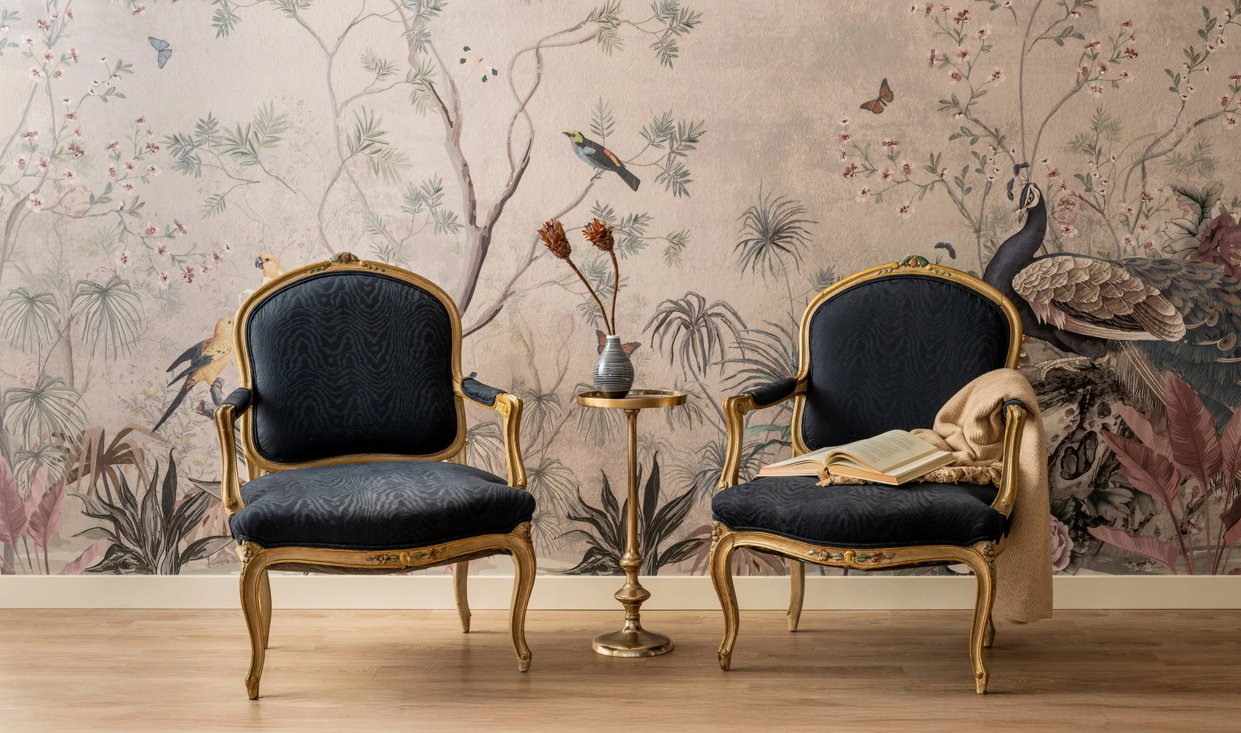 Black velvet French rococo armchairs with gold leaf accents against Chinoiserie mural wallpaper in a Bainbridge Island showroom.