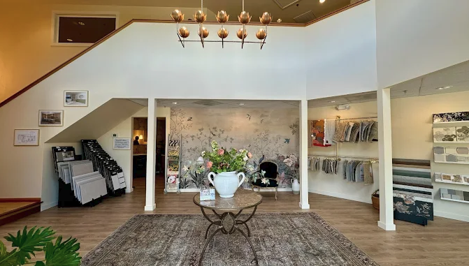 Bainbridge Island interior design showroom featuring a botanical mural wall, modern gold lotus chandelier, tile displays, and fabric samples.