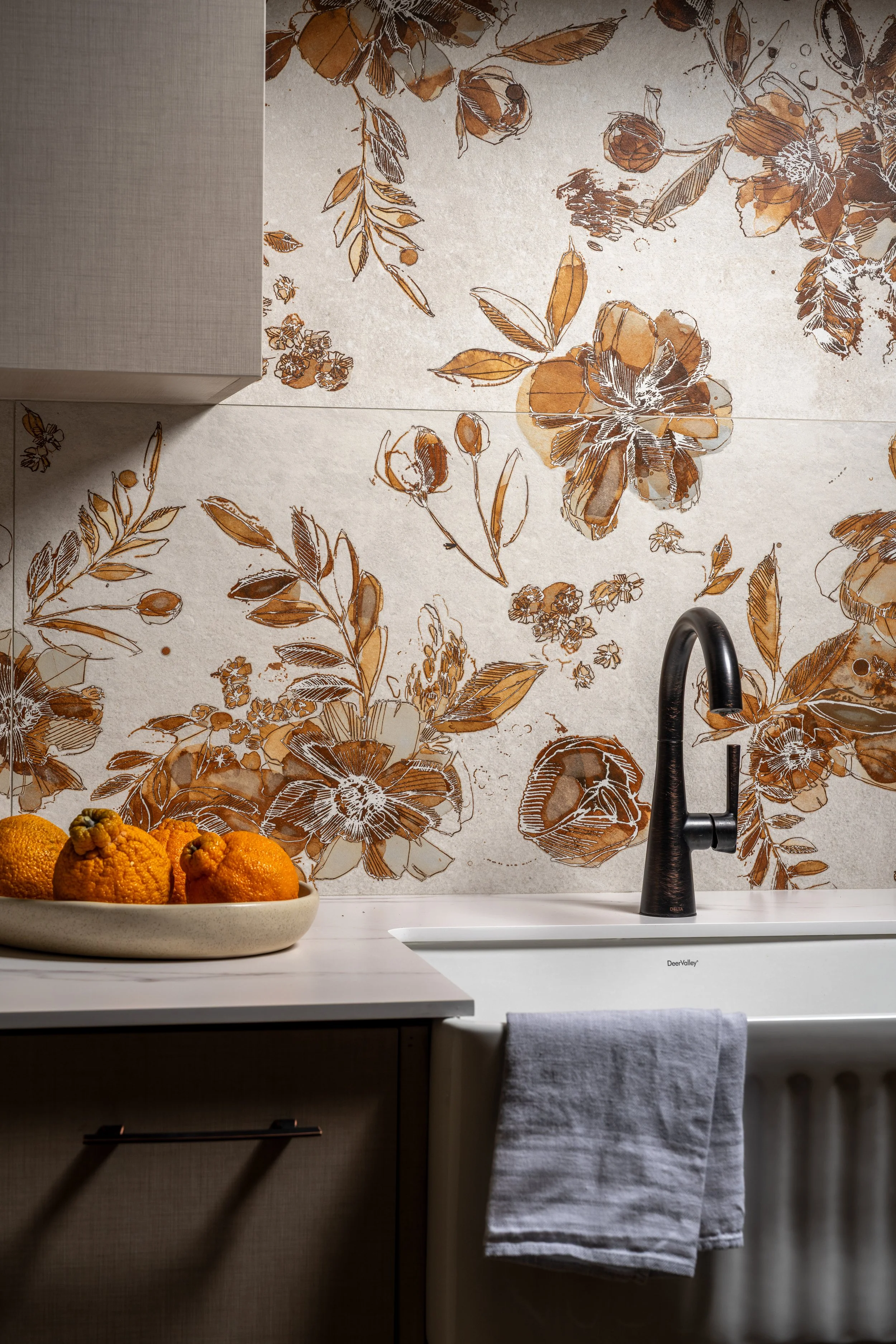 Bainbridge Island showroom kitchen featuring an illustrated floral tile backsplash, matte black gooseneck faucet, and white farmhouse sink.