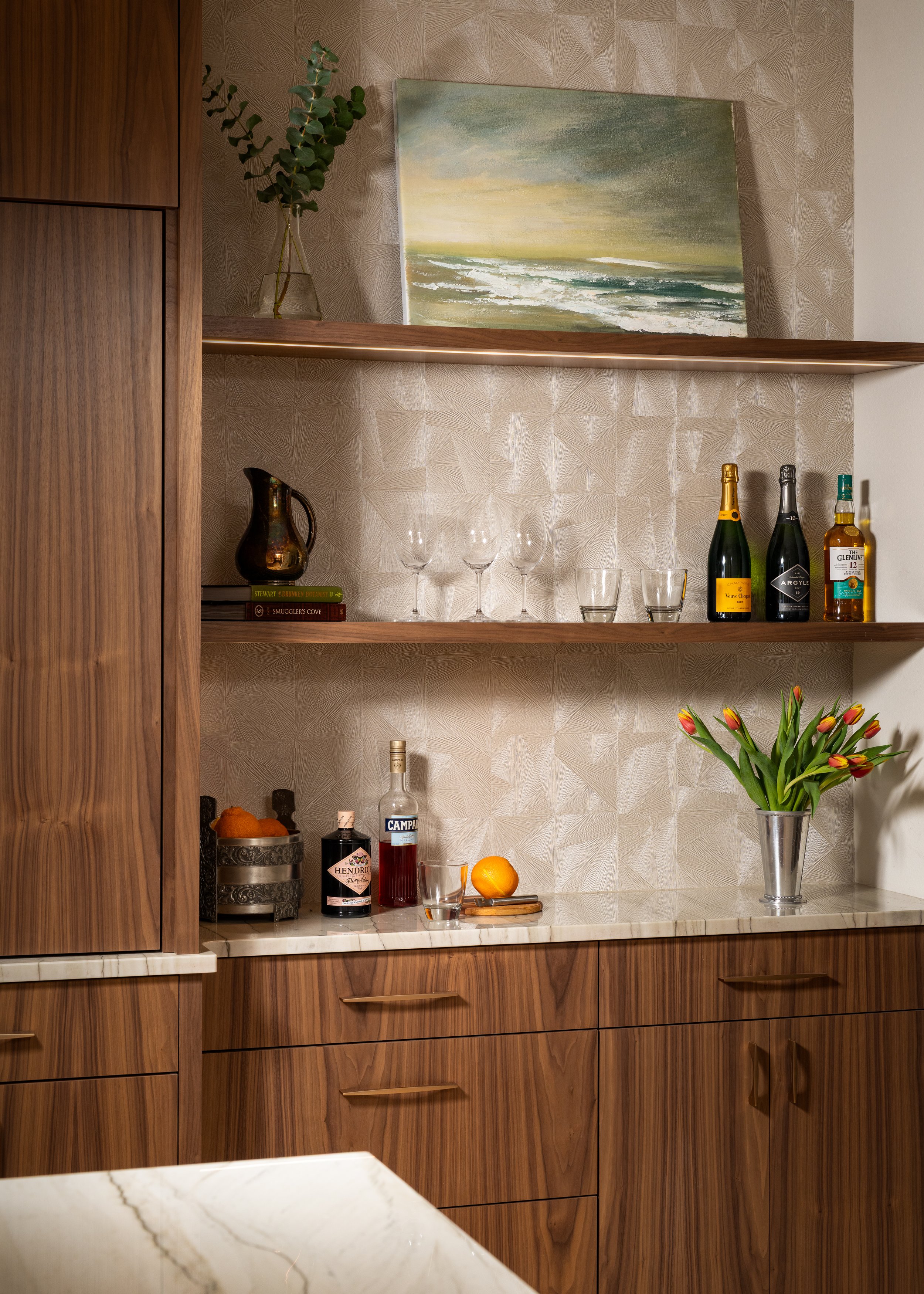 Bainbridge Island modern home bar with custom walnut cabinetry, marble countertop, textured geometric wallpaper, and floating wood shelves.