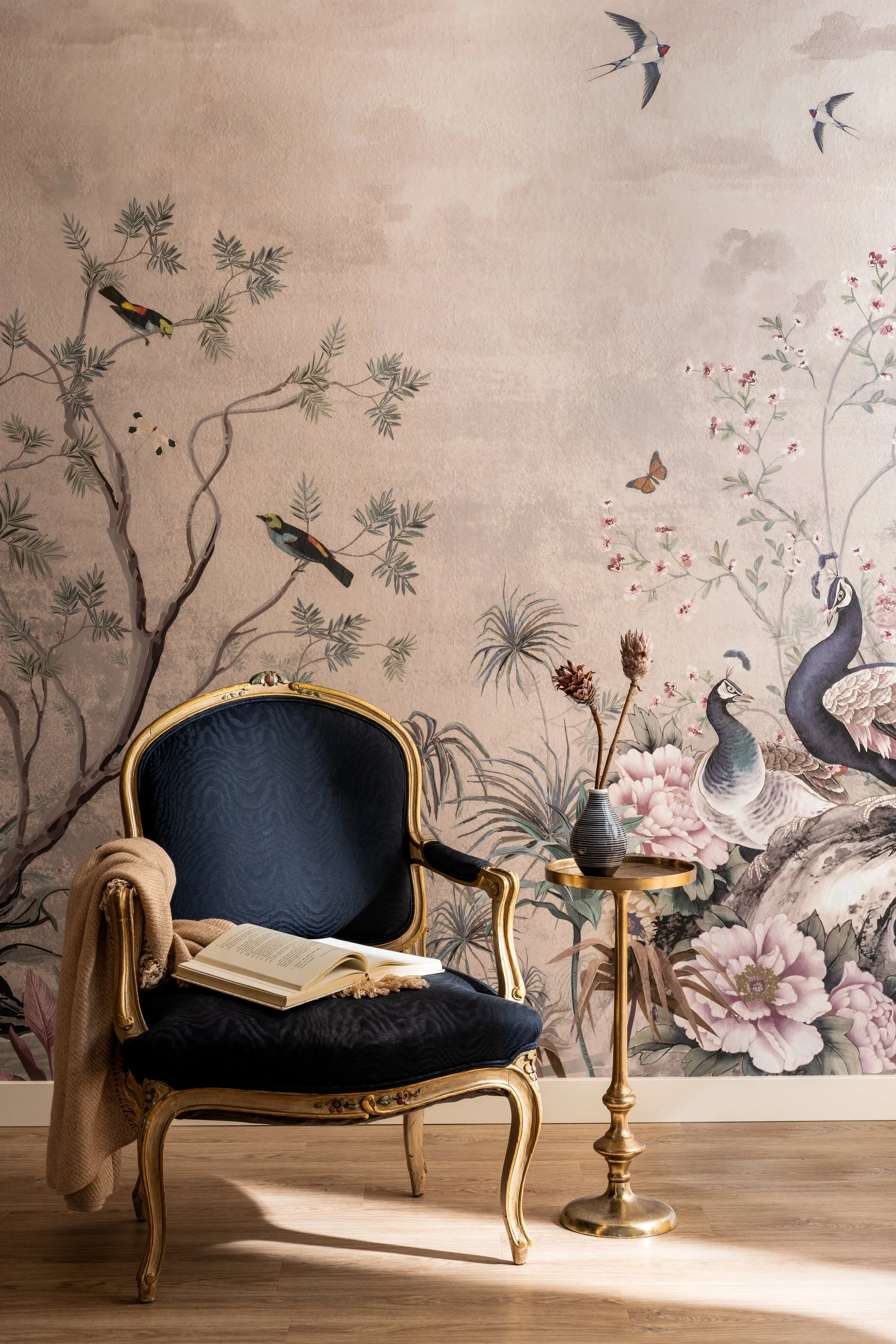 Gilded French armchair with black velvet upholstery against Chinoiserie mural wallpaper and brass pedestal side table on Bainbridge Island.