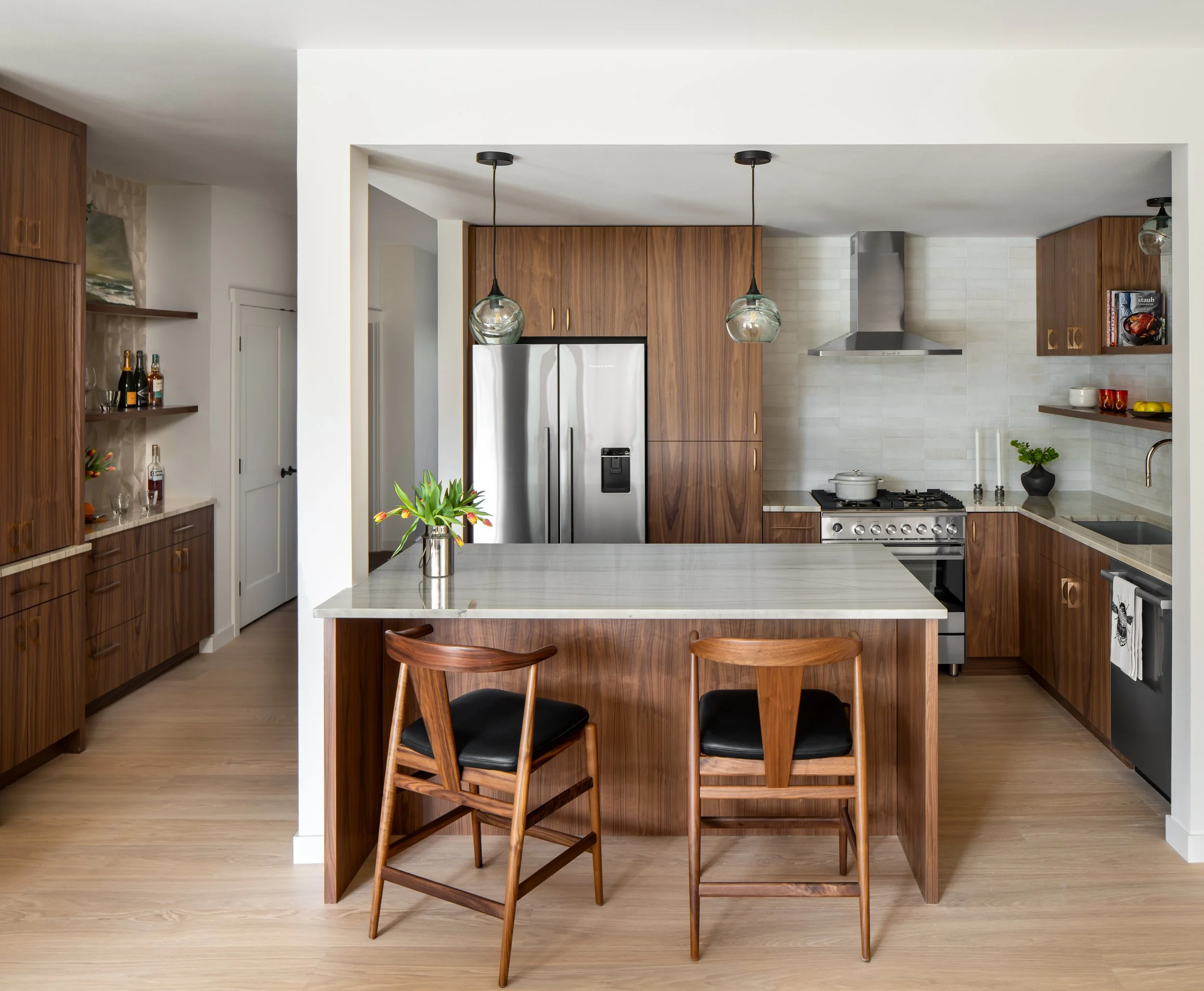 Bainbridge Island kitchen renovation featuring walnut cabinetry, marble island countertop, globe pendant lights, and mid-century modern bar stools.