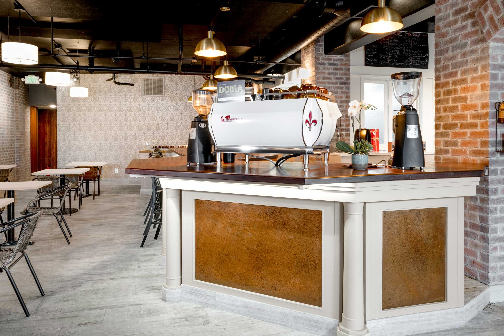 Inside Coquette Bakery's interior: a bespoke counter with brass accents, exposed brickwork, and curated lighting for an editorial aesthetic.