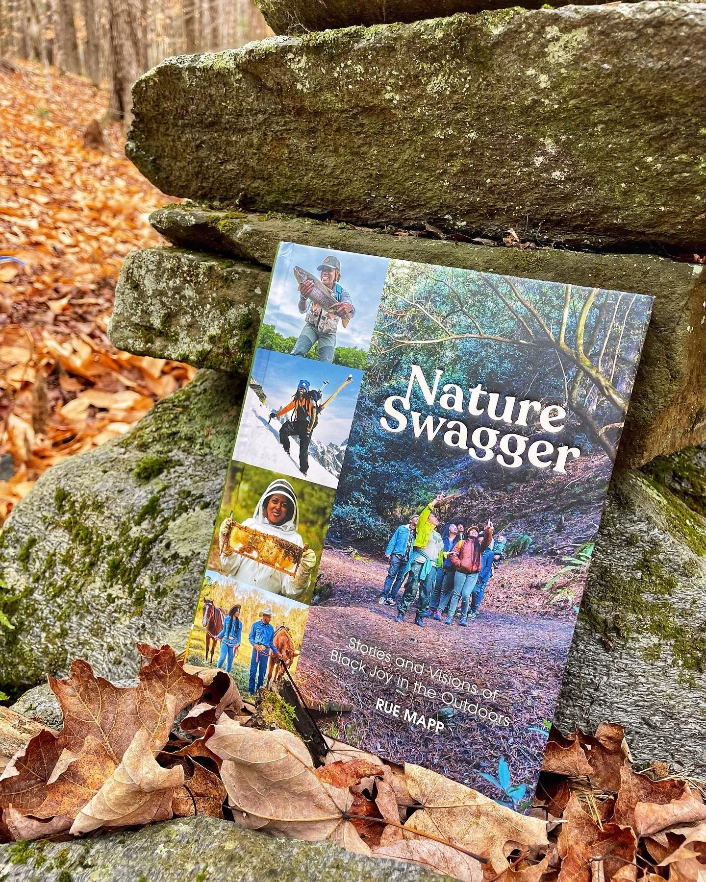 Brochure titled "Nature Swagger" displayed outdoors among fallen autumn leaves and moss-covered rocks, featuring photos of various outdoor activities and groups of people exploring a forested area.