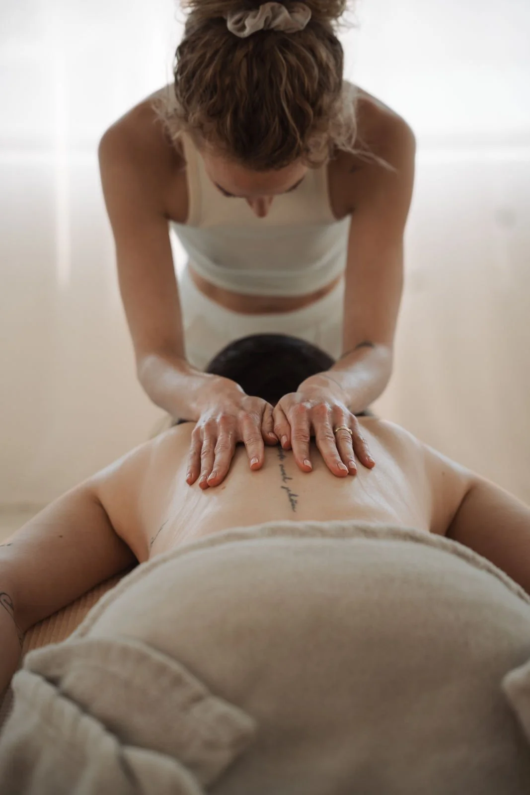 Eine Person, die eine Massage erhält, liegt entspannt auf einer Liege, während eine Masseurin sie behandelt.