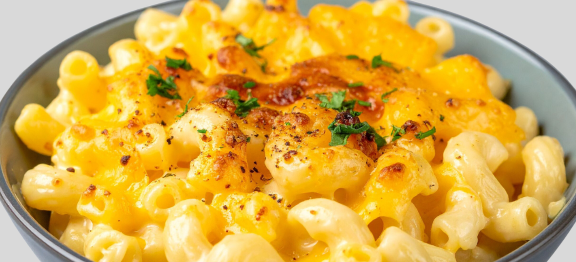 Close-up of a bowl of baked macaroni and cheese topped with melted cheese, garnished with chopped parsley.