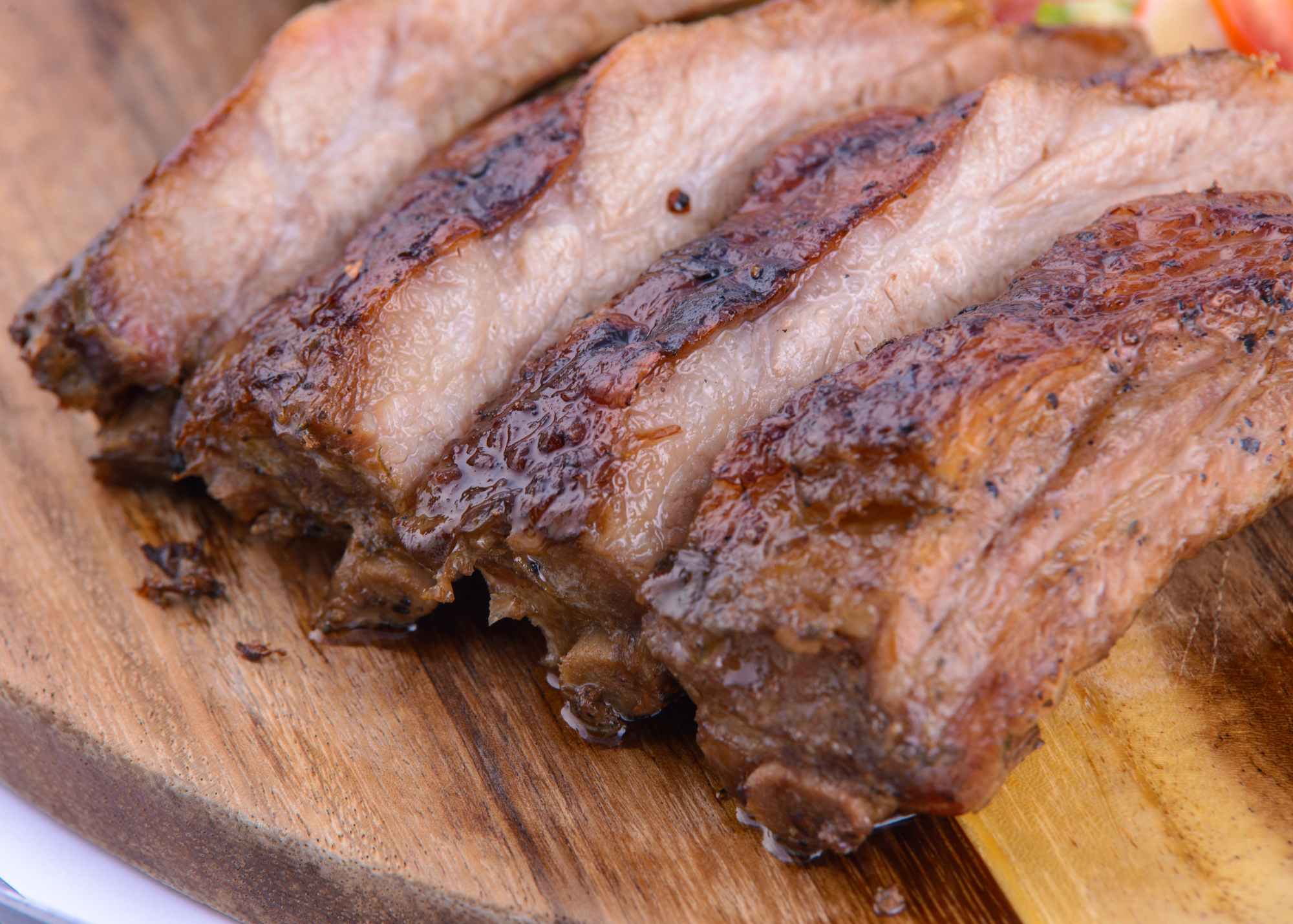 Close-up of grilled pork ribs on a wooden cutting board.