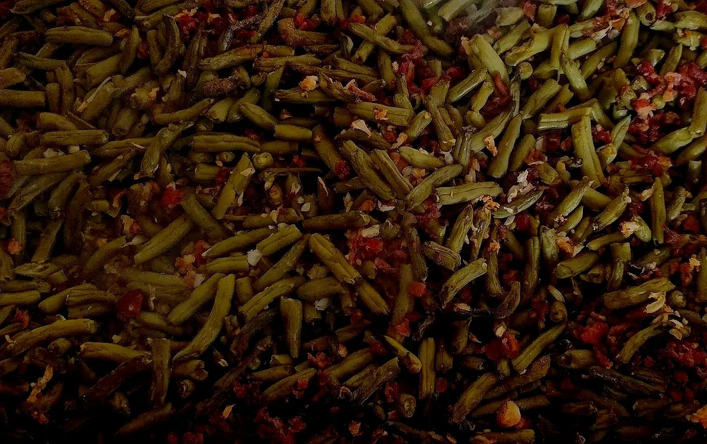 Close-up image of cooked green beans with bits of bacon.