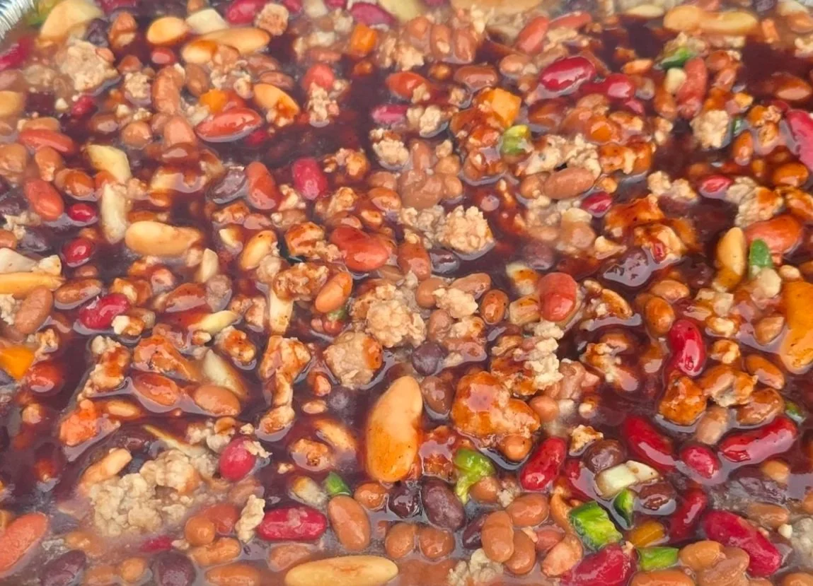 Close-up of a pot of cooked chili with ground meat, beans, and chopped vegetables in a thick sauce.