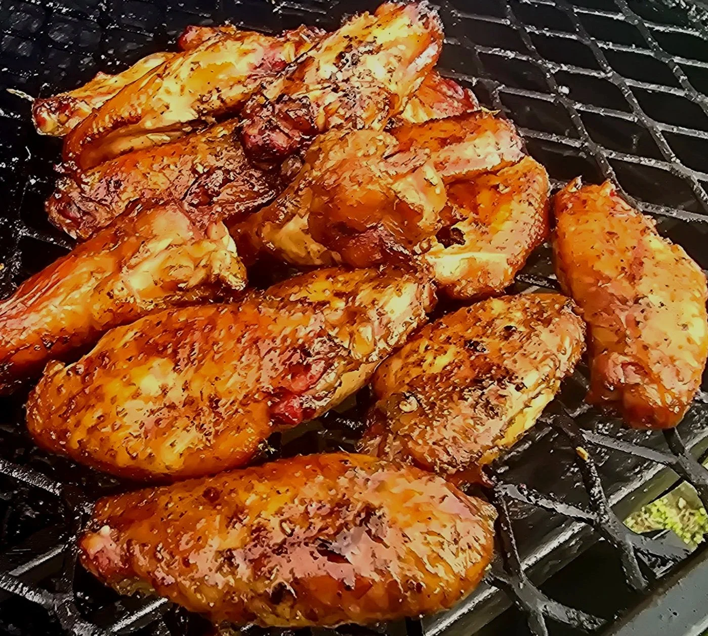 Grilled chicken breasts with a glazed, seasoned coating on a barbecue grill.