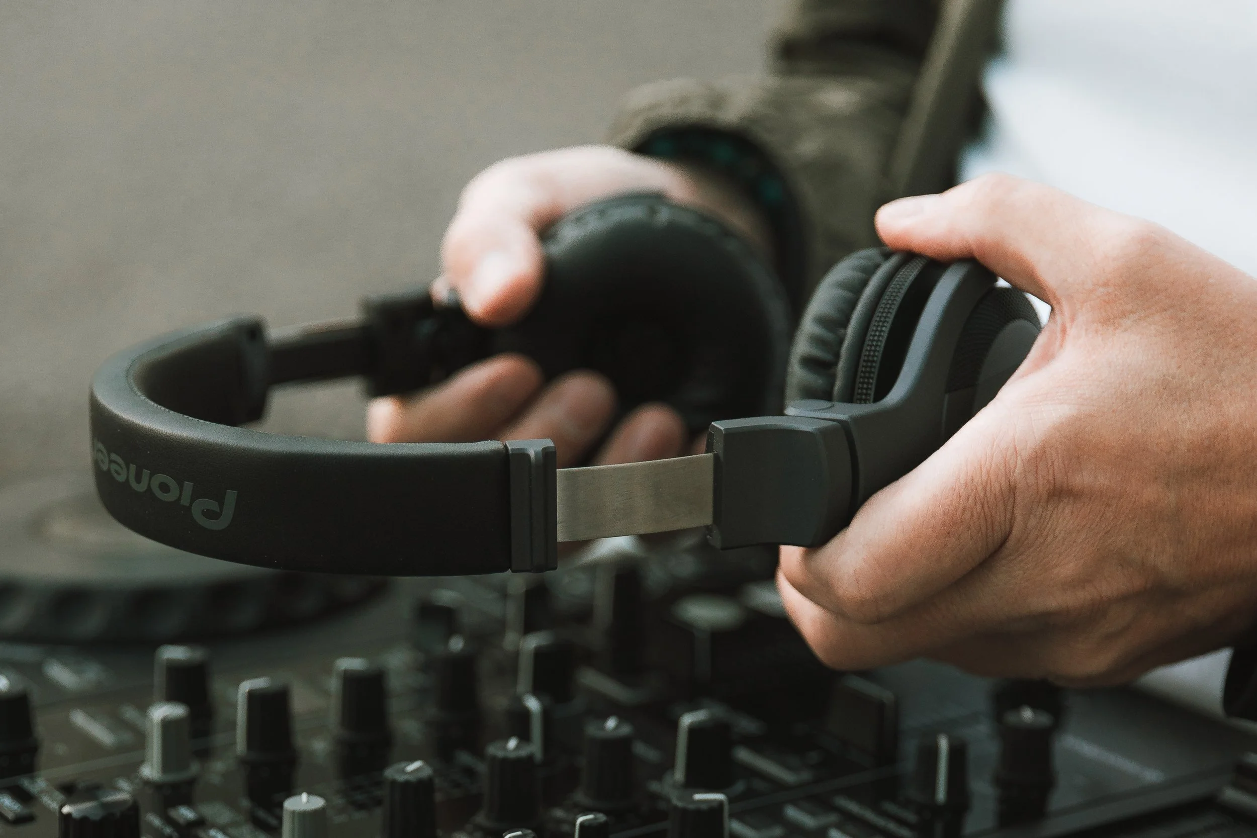 Eine Person stellt ein Paar Kopfhörer auf einen DJ-Mischpult