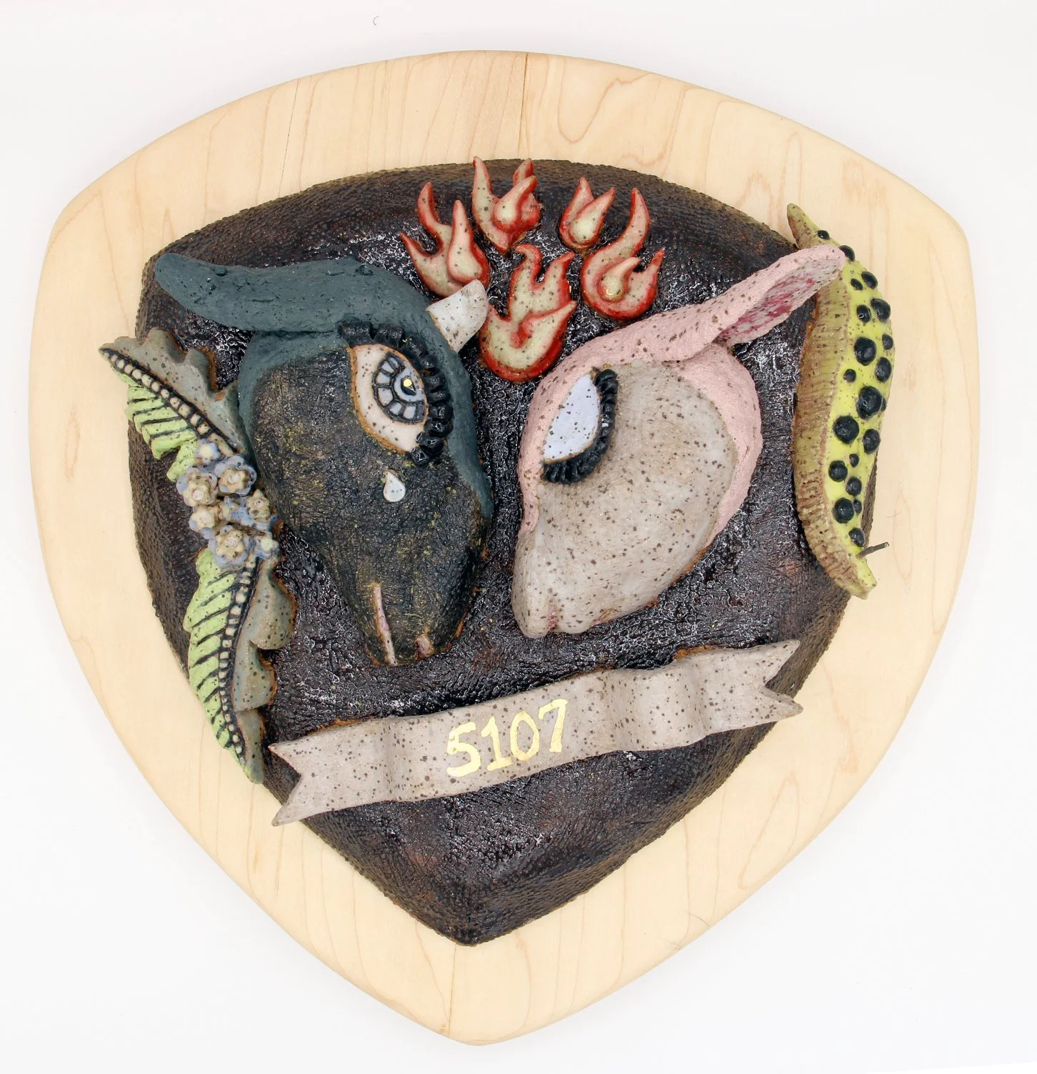 A cake designed with animal faces, flames, and leaves, arranged on a heart-shaped base with a wooden border, and labeled with 'S107'.