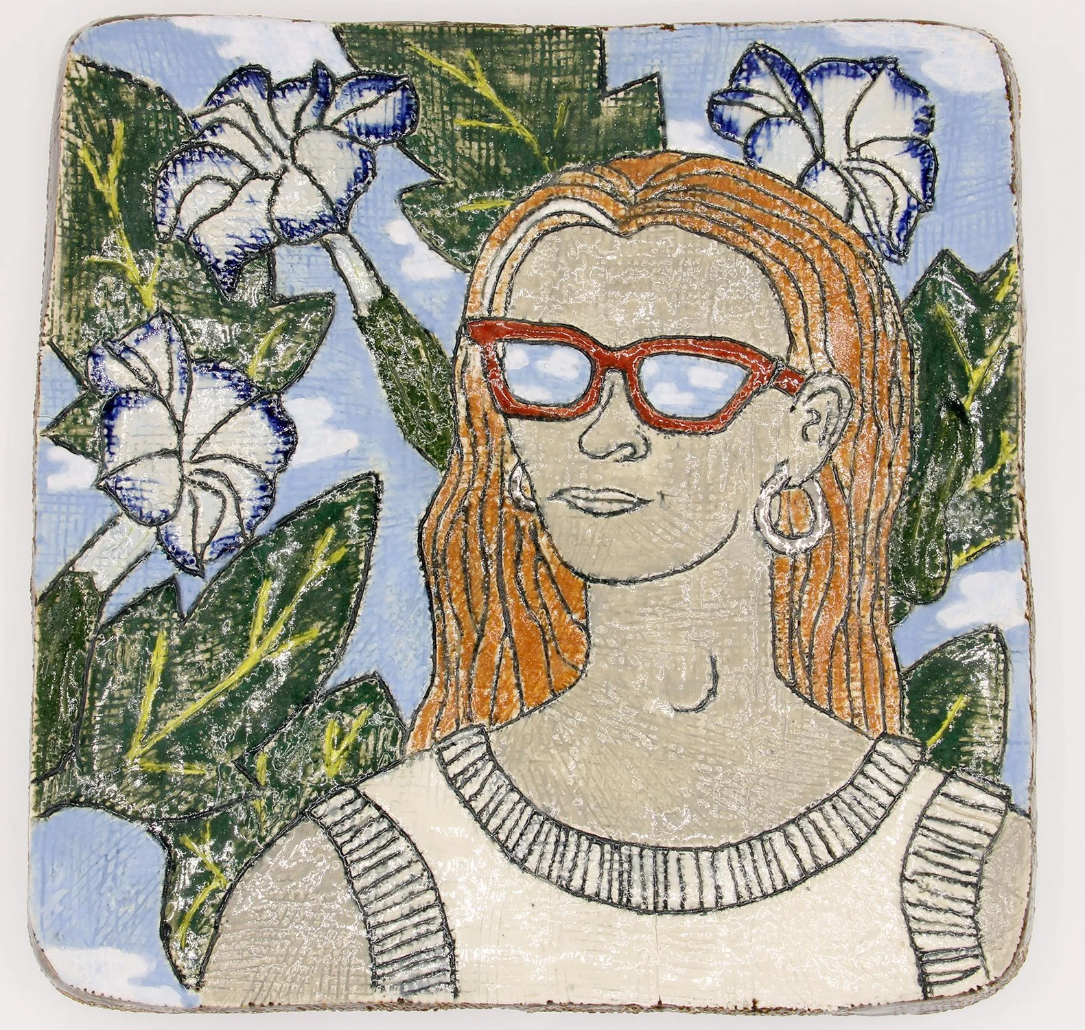 Decorative ceramic tile art of a woman with orange hair, glasses, earrings, and a sleeveless top, surrounded by blue and white flowers and green leaves, with a sky-blue background.