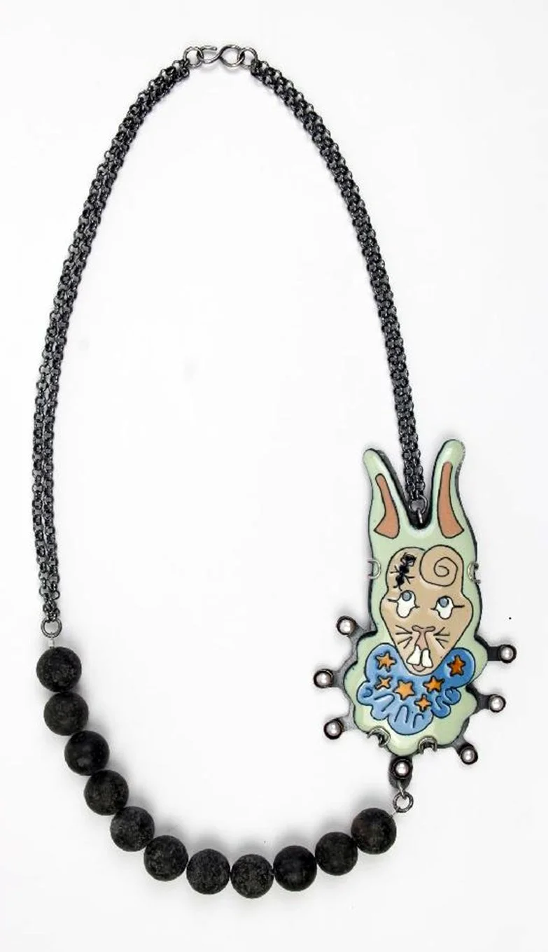 A necklace with a chain made of small black beads and a larger bead on each end, featuring a bunny-shaped pendant with a cartoonish face, large ears, and a blue collar with orange stars.