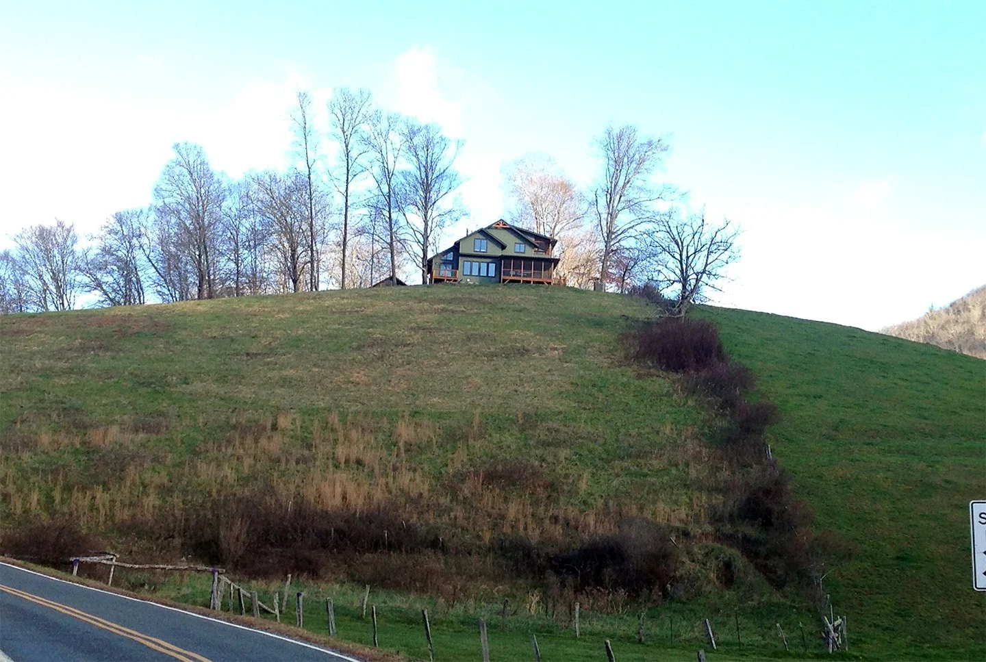 House on hilltop with trees and clear sky in the background