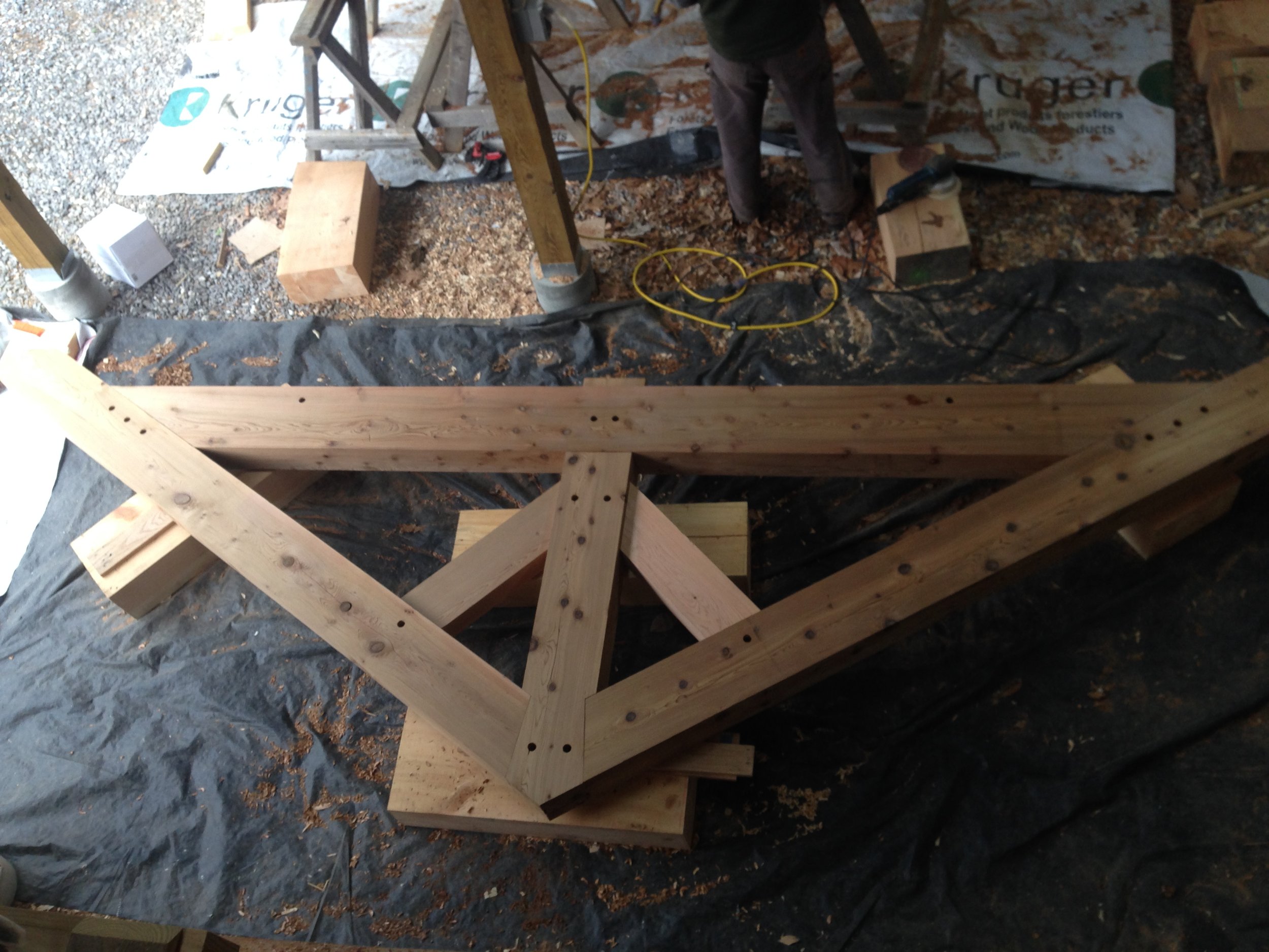 Wooden framework under construction in a workshop, with various tools and materials around.