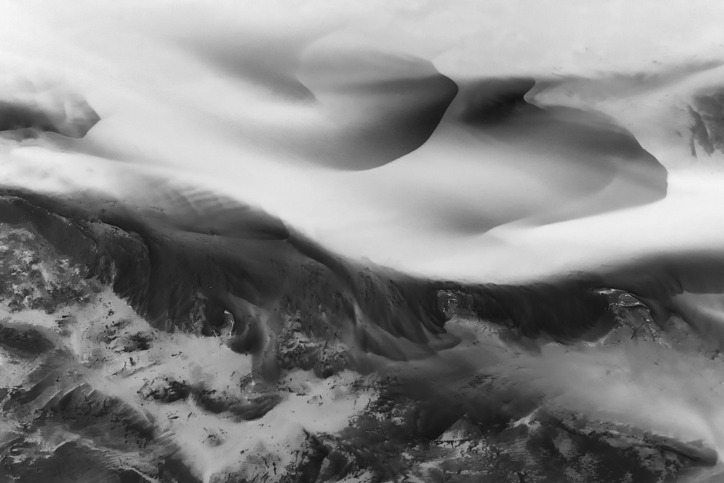 Black and white photo of glacier ice and rugged rocks with jagged edges.